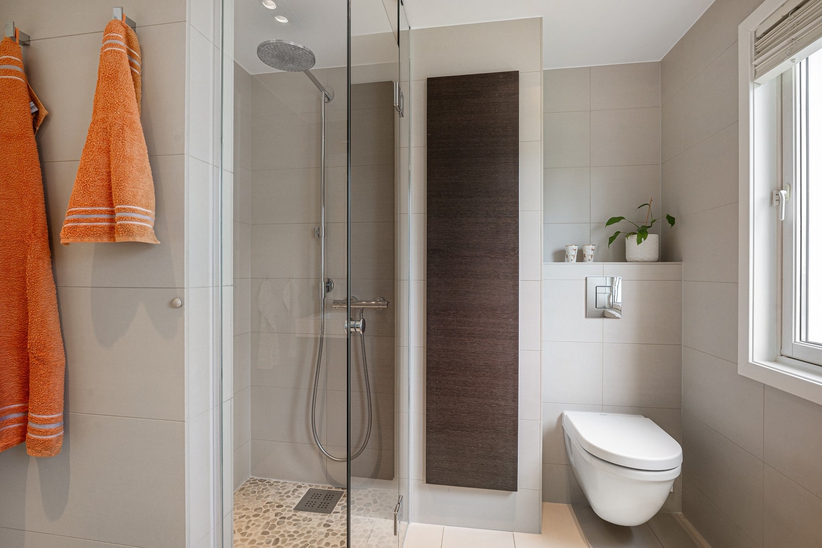 Dusjhjørne med glassdør, regnfallsdusj og veggmontert toalett gir badet en praktisk og moderne funksjon. Galleribilde