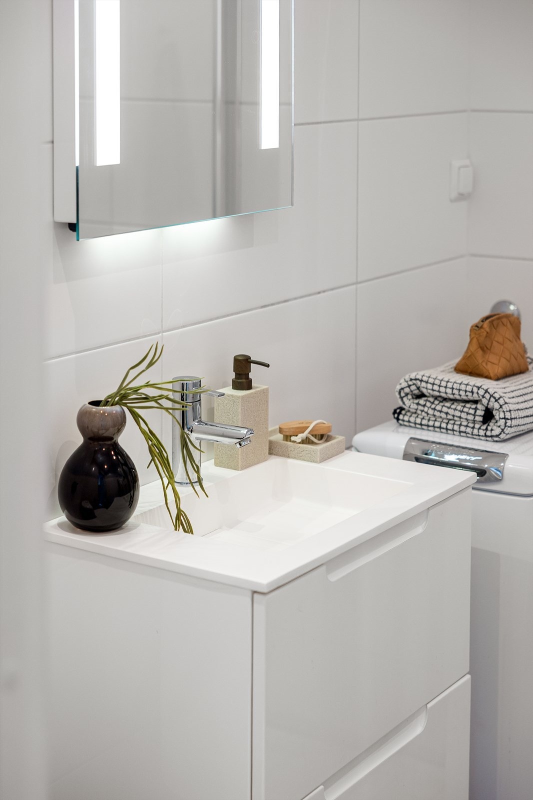 Badet er utstyrt med servantinnredning, dusjhjørne med glassdører og opplegg for vaskemaskin. Galleribilde