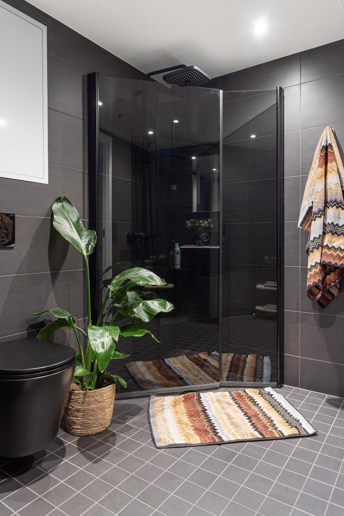 Badet er innredet med vegghengt toalett og dusjhjørne med innfellbare glassdører som frigjør plass på gulvet. Galleribilde