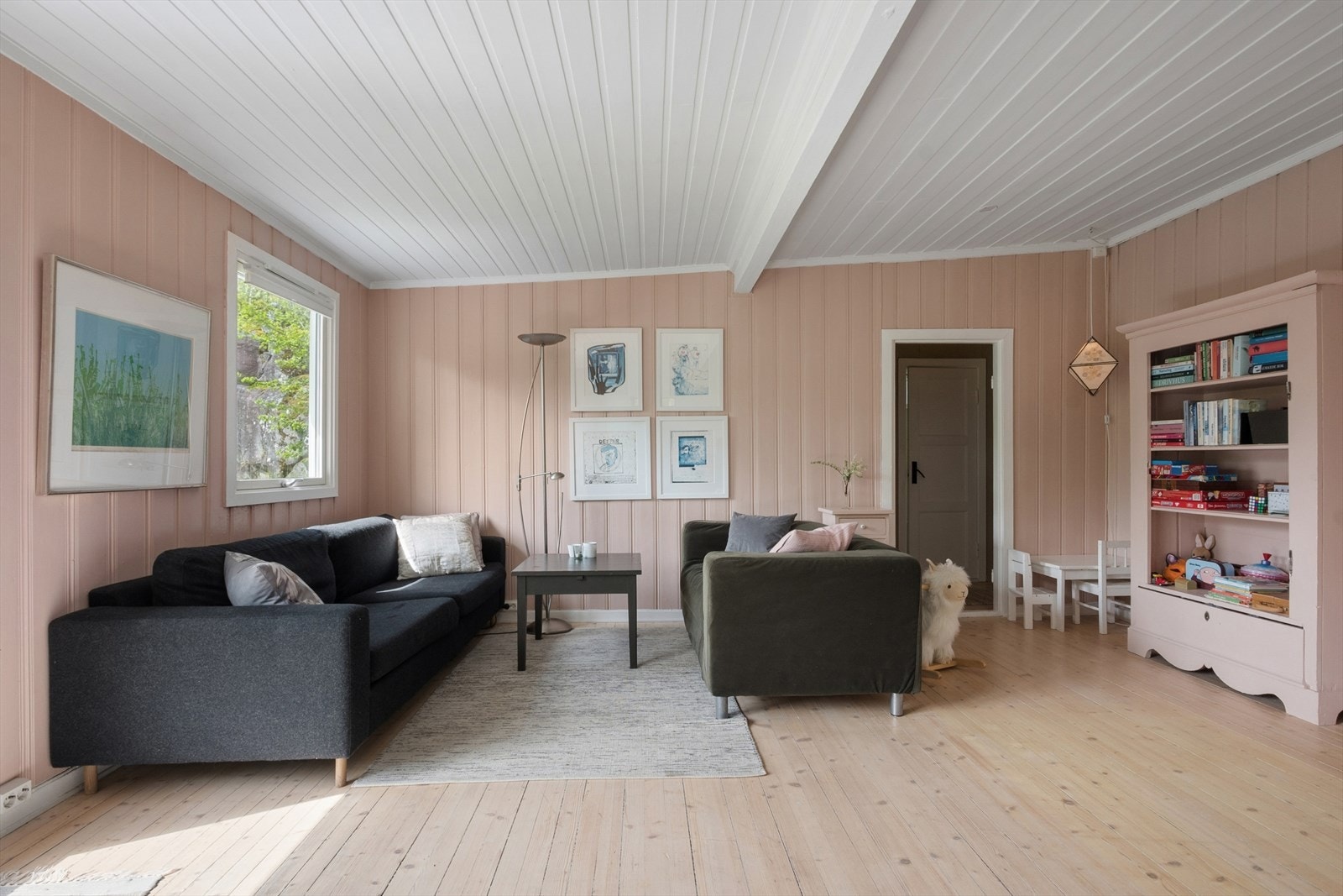 Stuen har god plass til sofagruppe. Gjennomgående furugulv og malt panel skaper en helhetlig atmosfære. Galleribilde