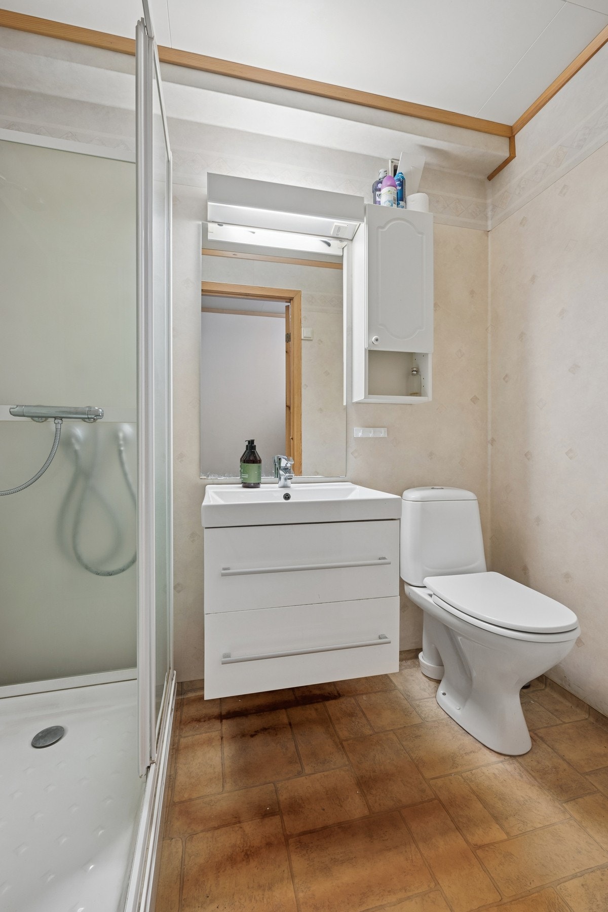 Badet er innredet med dusjkabinett, toalett og servant med speilskap. Galleribilde