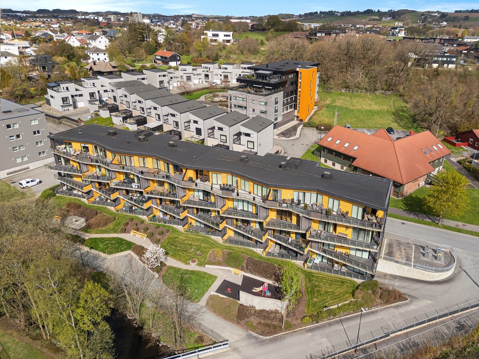 Oversiktsbilde som viser bygget og de grønne, fine fellesområdene. Galleribilde
