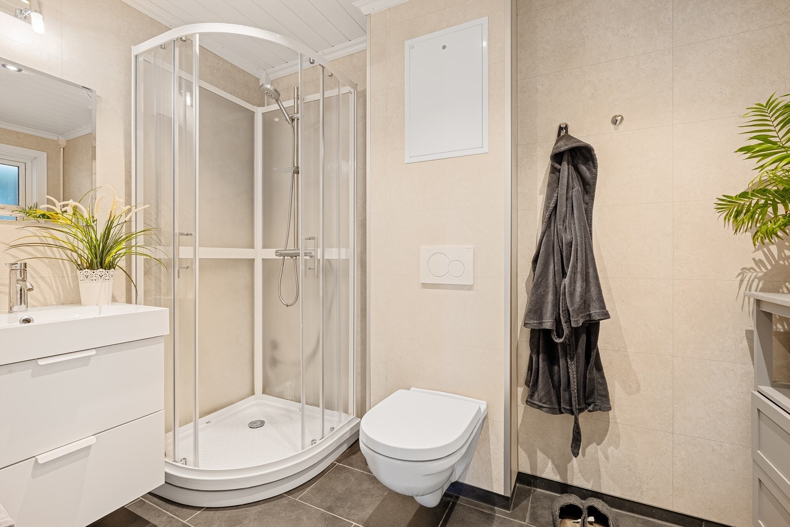 Badet i 1.etg. har fliser på gulvet med varmekabler, samt våtromsplater på veggene. Det inneholder et vegghengt toalett, dusjkabinett, samt baderomsinnredning med speil og belysning over. Galleribilde