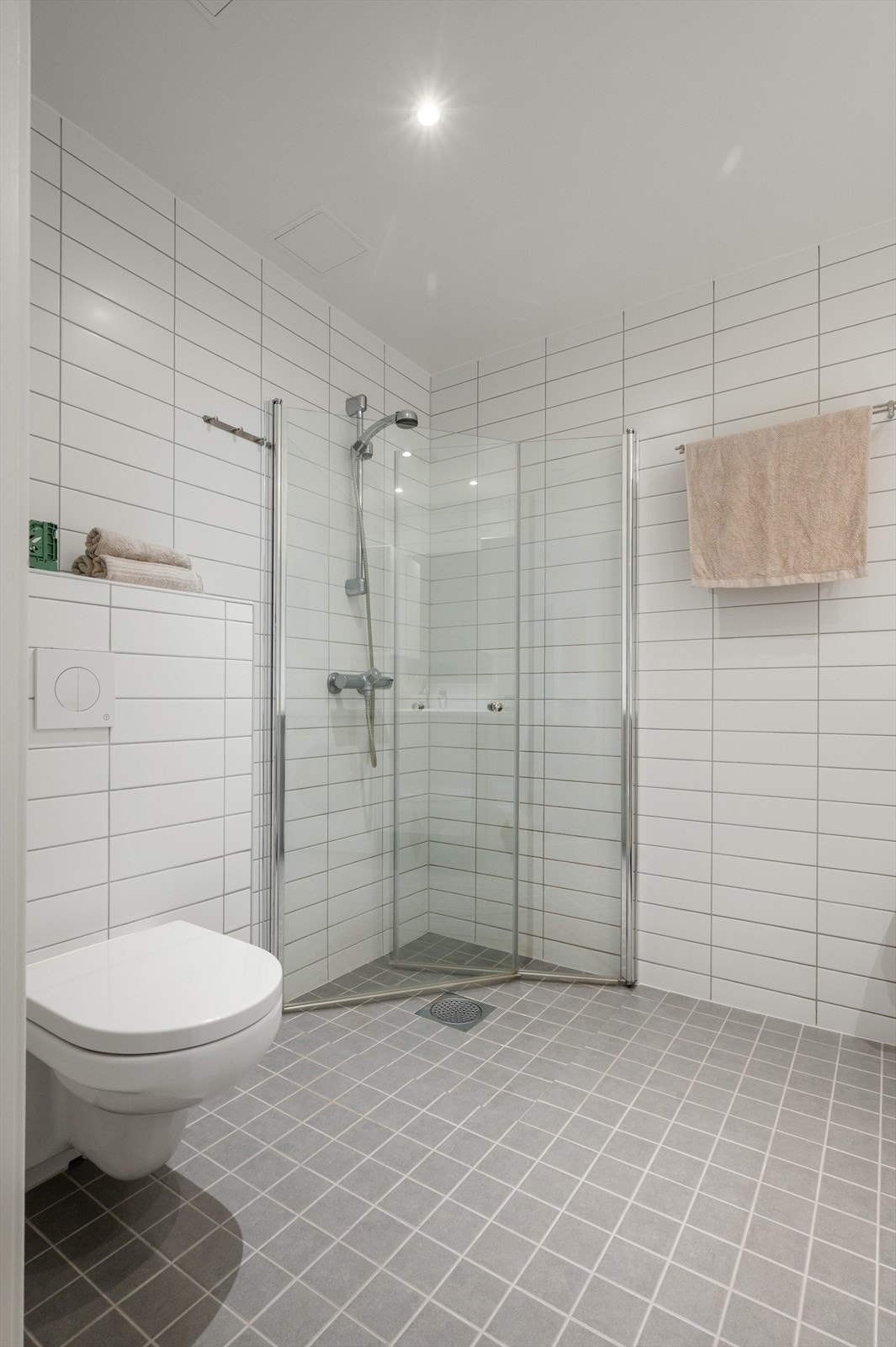 Videre er det dusjhjørne med svingbare glassdører, vegghengt toalett med innebygget sisterne og opplegg for vaskemaskin. Galleribilde