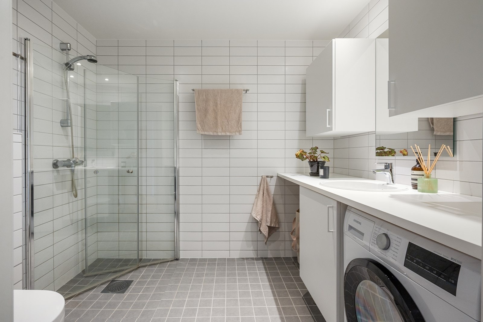 Romslig og pent baderom med heldekkende benkeplate, innfelt servant, underskap, overskap og speil. Galleribilde