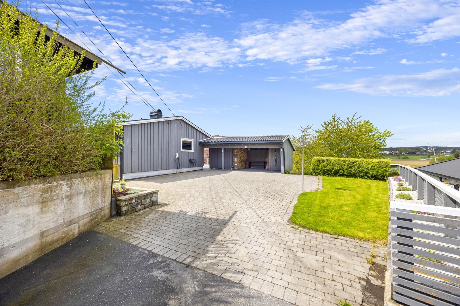 Innkjørsel med belegningsstein og carport, samt to uteboder. Galleribilde