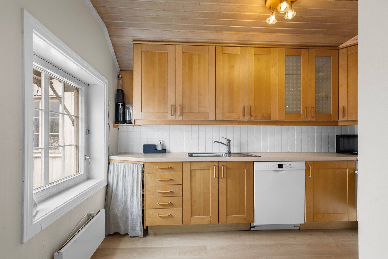 Lyst kjøkken i skandinavisk stil med plass til hvitevarer og vindu mot uteområdet. Galleribilde