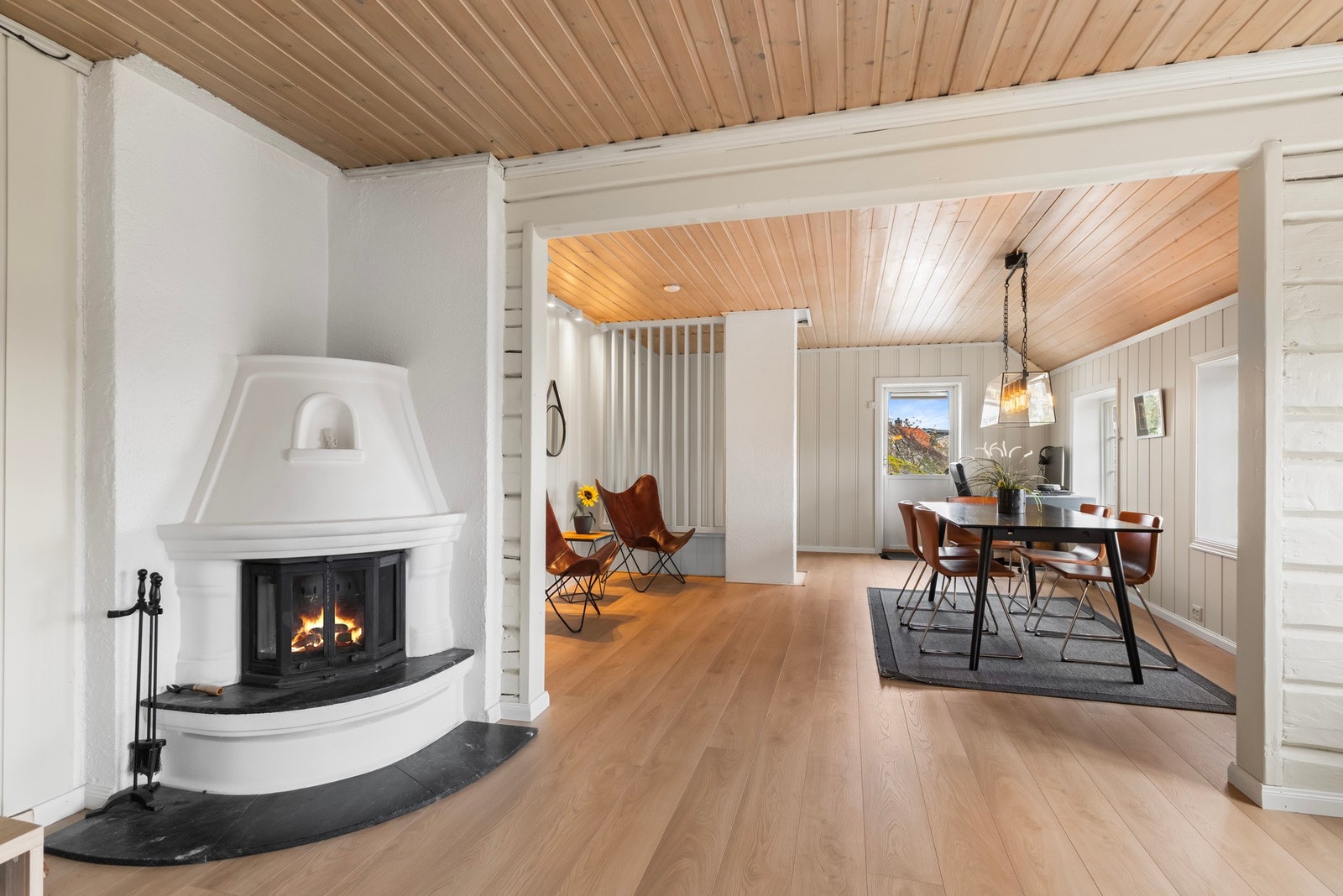 Lys stue med peisinnsats, lune materialvalg og åpen forbindelse mot spisestuen. Galleribilde