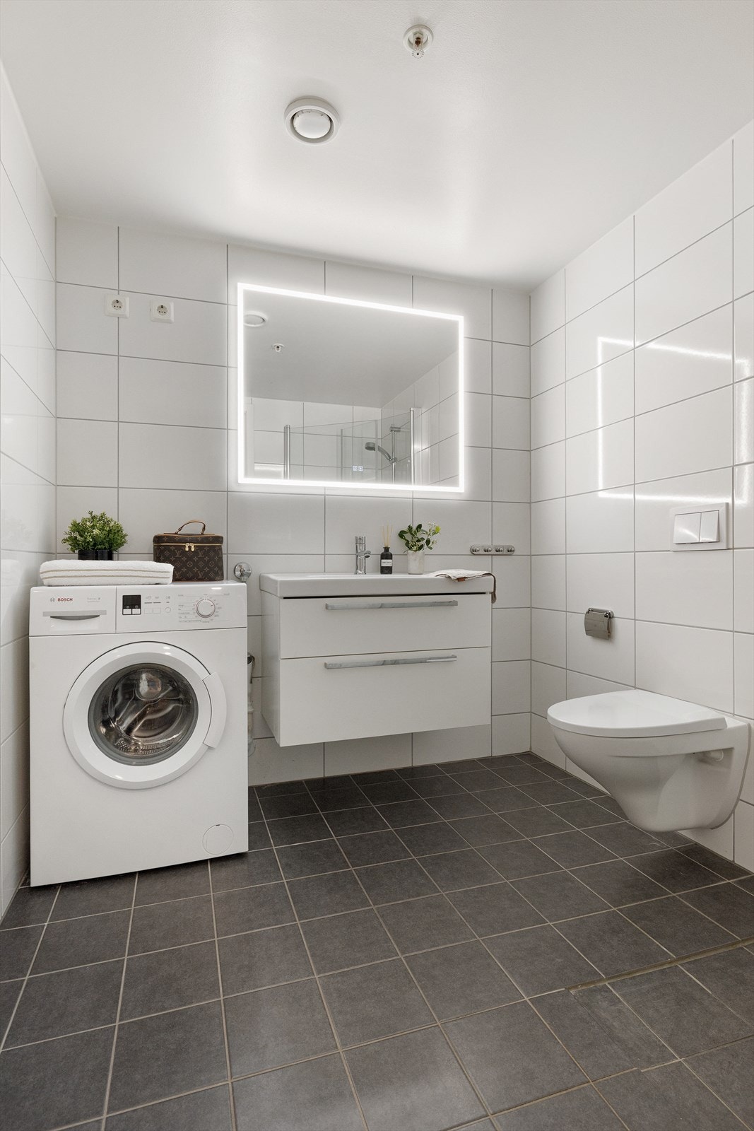 Pent bad med gulvvarme og moderne innredning. Badet er utstyrt med dusjhjørne med innfellbare dusjdører og dusjgarnityr i krom, servantskap med hvite, slette fronter og keramisk servant med ettgreps armatur i krom. Galleribilde