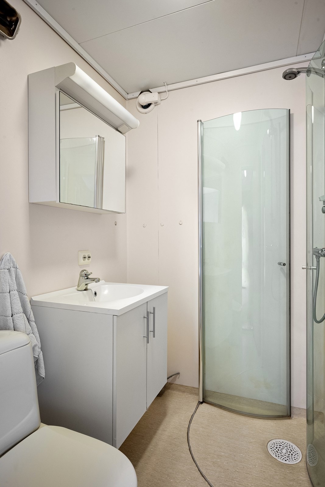 Badet har gulvbelegg, veggvinyl, dusjhjørne og servant med speilskap. Galleribilde