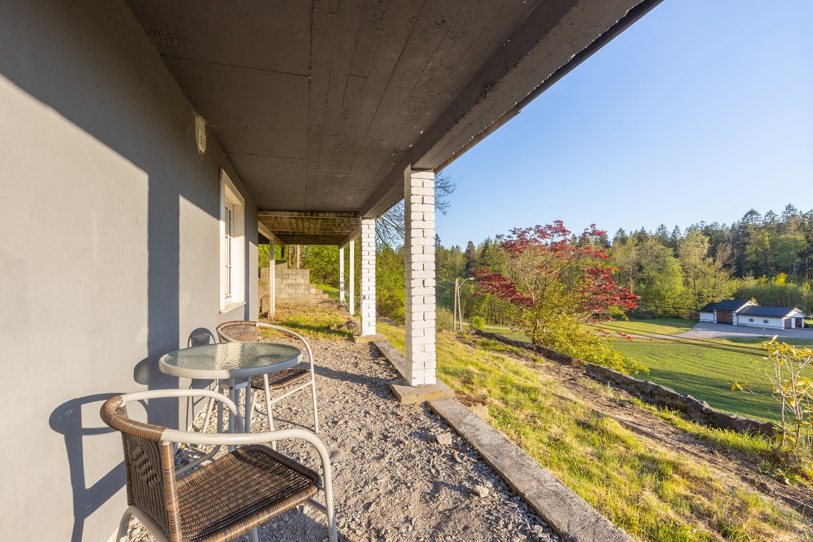 Hyggelig, gruslagt uteplass i tilknytning til underetasjen. Uteplassen er overbygd i form av terrasse ut fra stuen i hovedetasjen. Galleribilde