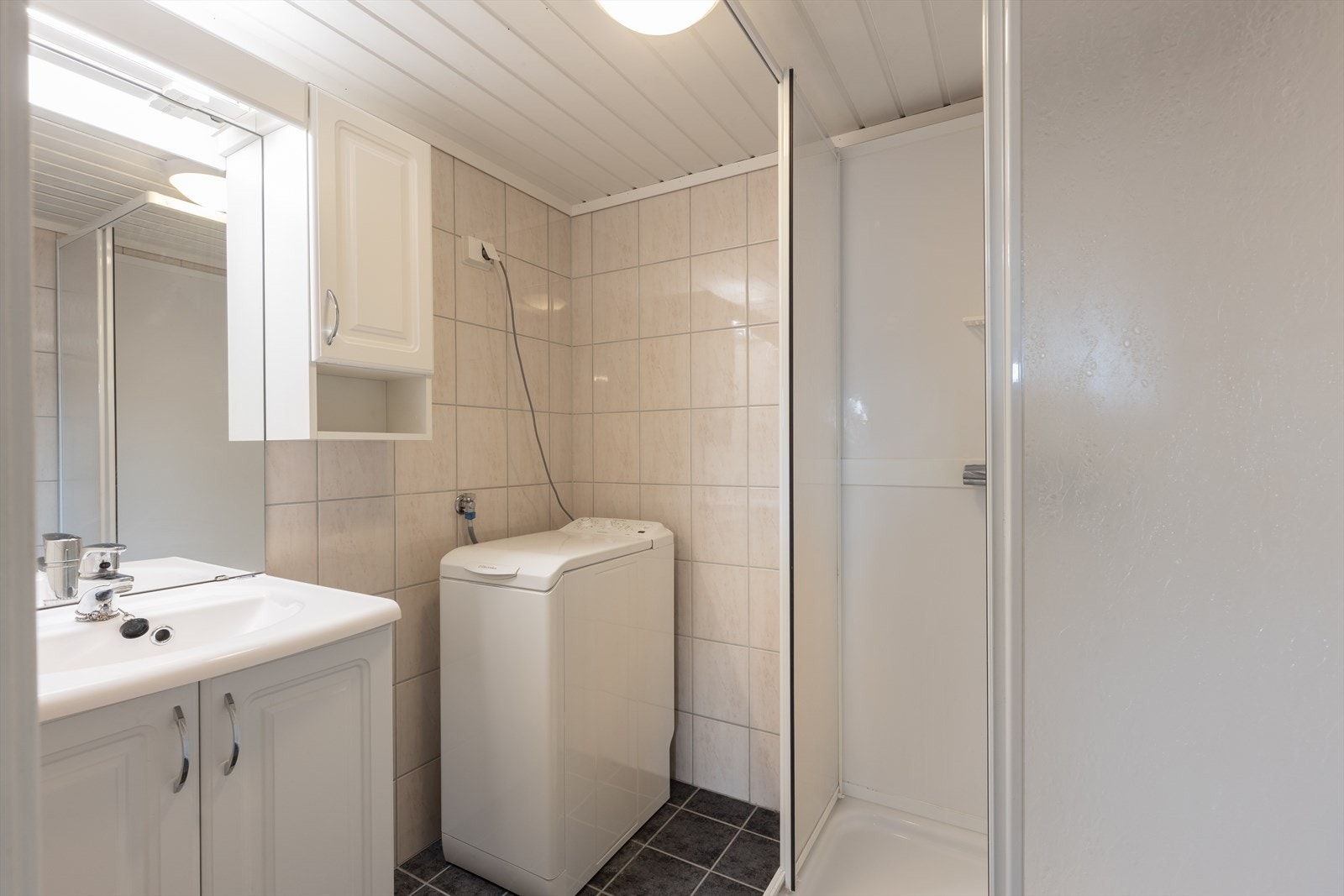 Det er flislagt bad med dusjkabinett, servantskap og opplegg for vaskemaskin. Ny avtrekksvifte ble satt inn i 2021. Galleribilde