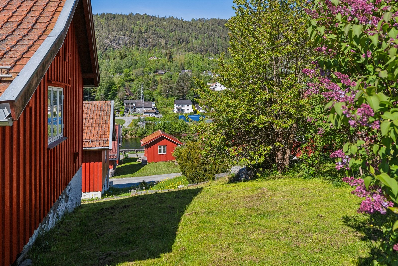 Tomten er skrånet, opparbeidet med plen og beplantninger. Galleribilde