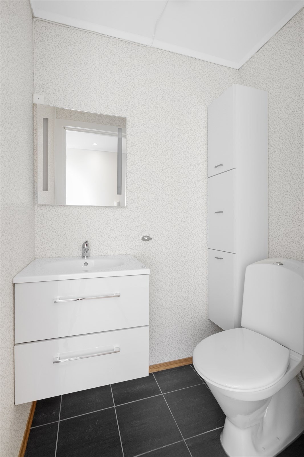 I entré ligger toalettrommet praktisk til, her er det fliser på gulv med varmekabler, tapet på vegg og malte plater i himling. Galleribilde