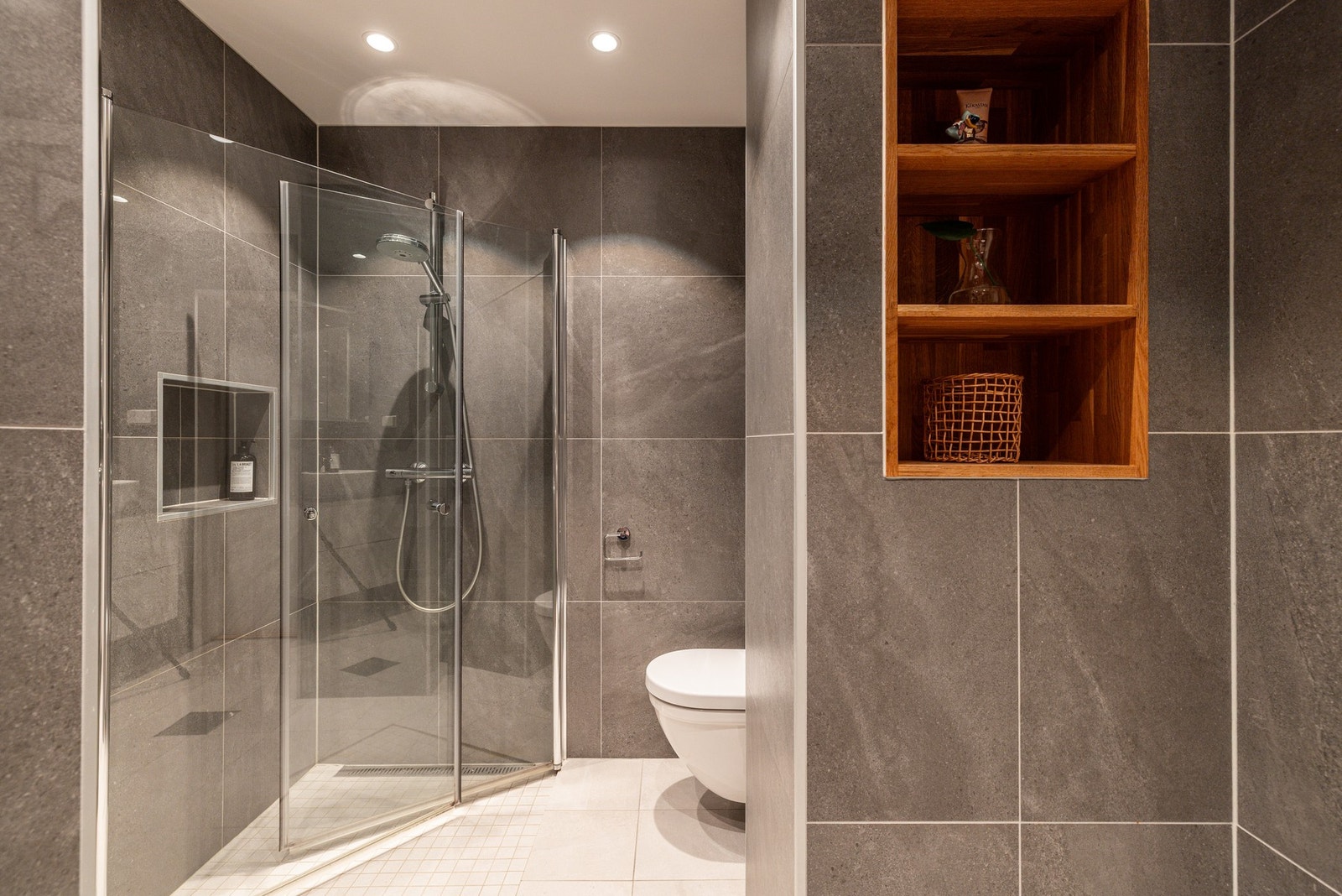 Badet har tidløse fliser, dekorative hyller og varmekabler på gulvet. Galleribilde