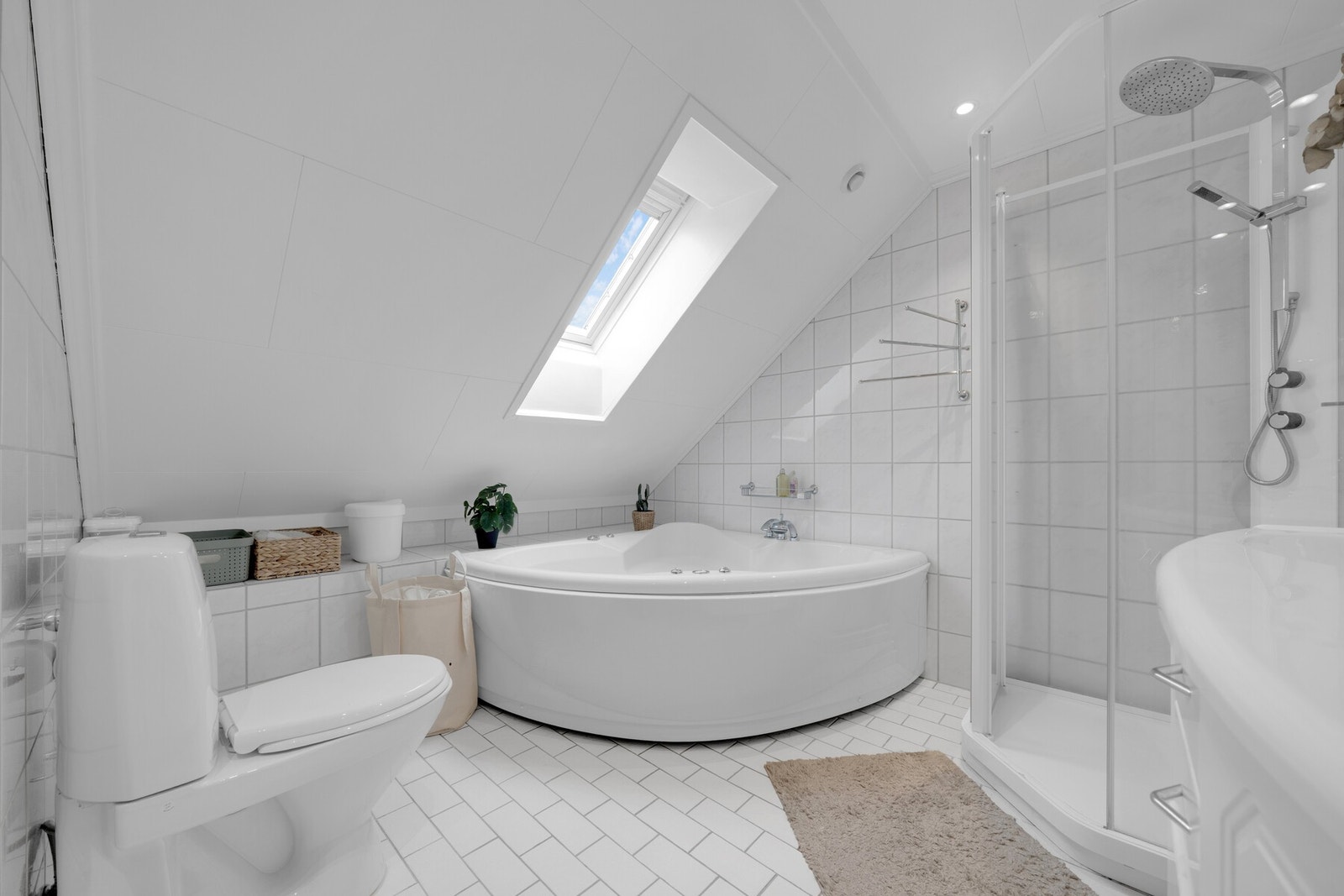 På badet er det både et dusjkabinett med regnfallsdusj og et hjørnebadekar med dyser Galleribilde