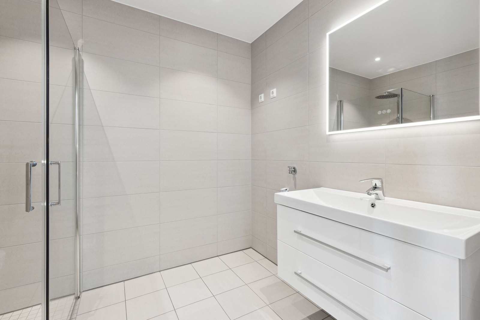 Lyst og pent bad i moderne utseende. Her har du hjørnedusj, toalett, baderomsinnredning og speil med belysning og det er opplegg for vaskemaskin og tørketrommel på badet. Galleribilde