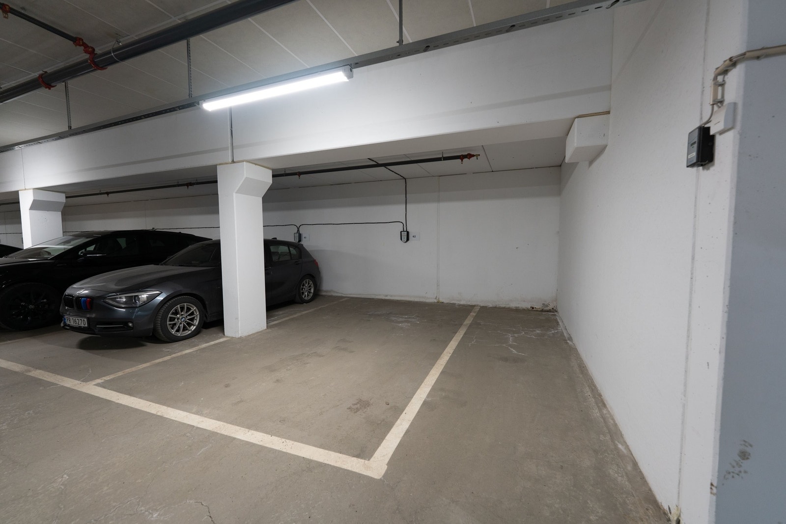 En av de garasjeplassene med best beliggenhet i prosjektet, plassert i hjørnet med egen elbil lader i varm garasjekjeller Galleribilde