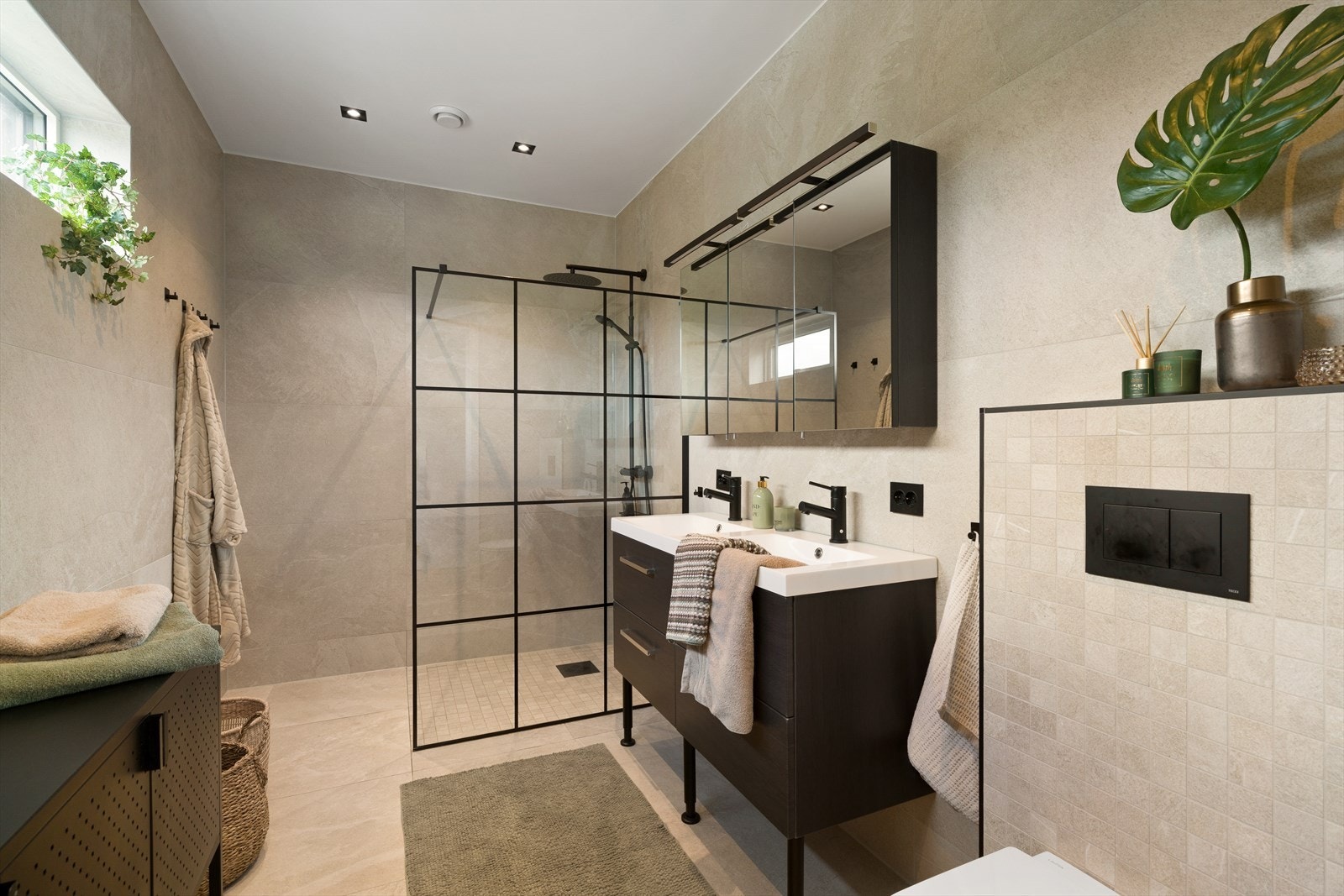Etasjen inneholder også et delikat bad med helflisede overflater og varmekabler i gulv. Badet er utstyrt med servant, speilskap, vegghengt toalett og dusj. Galleribilde