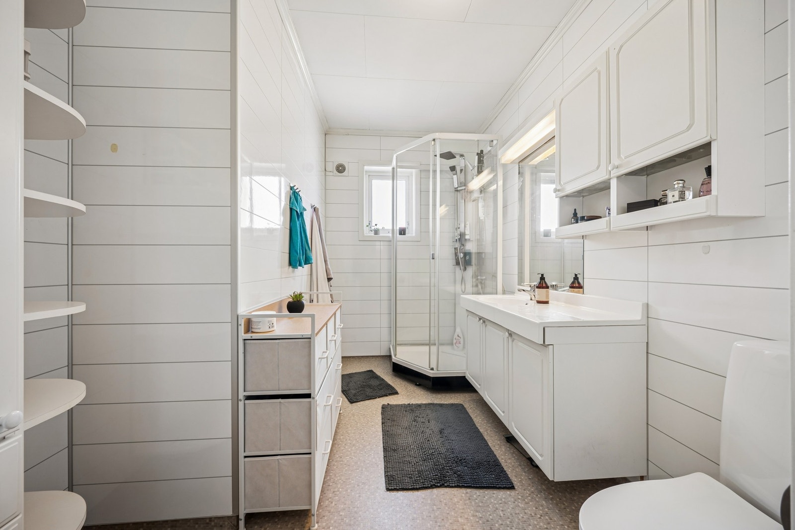 Badet har baderomsplater på veggene, belegg på gulv og et praktisk dusjkabinett. Galleribilde