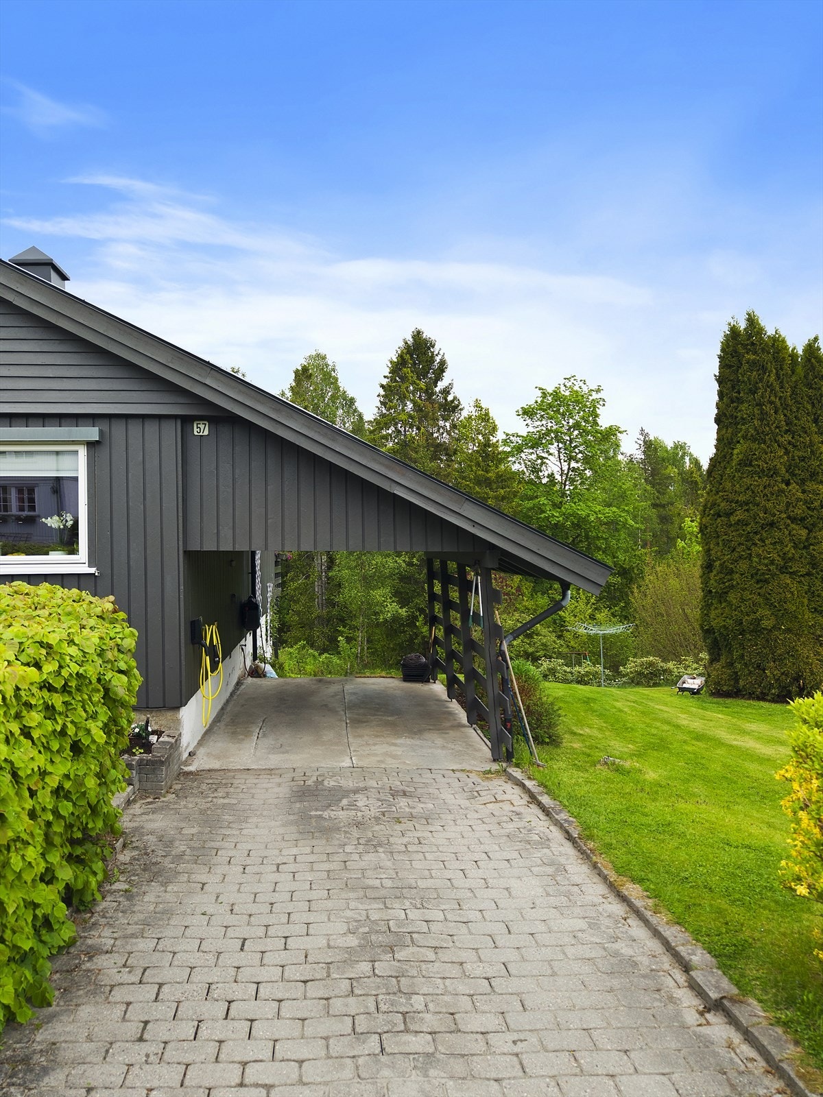 Carport med tilhørende gårdsplass. Det er montert elbillader. Galleribilde