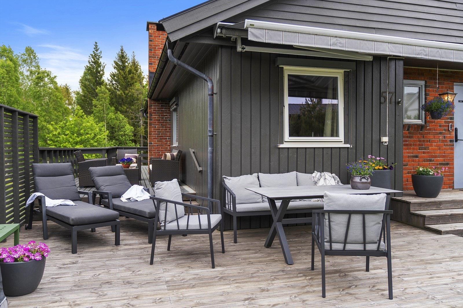 Stor terrasse som strekker seg langs deler av huset, med flere soner for avslapning. Galleribilde