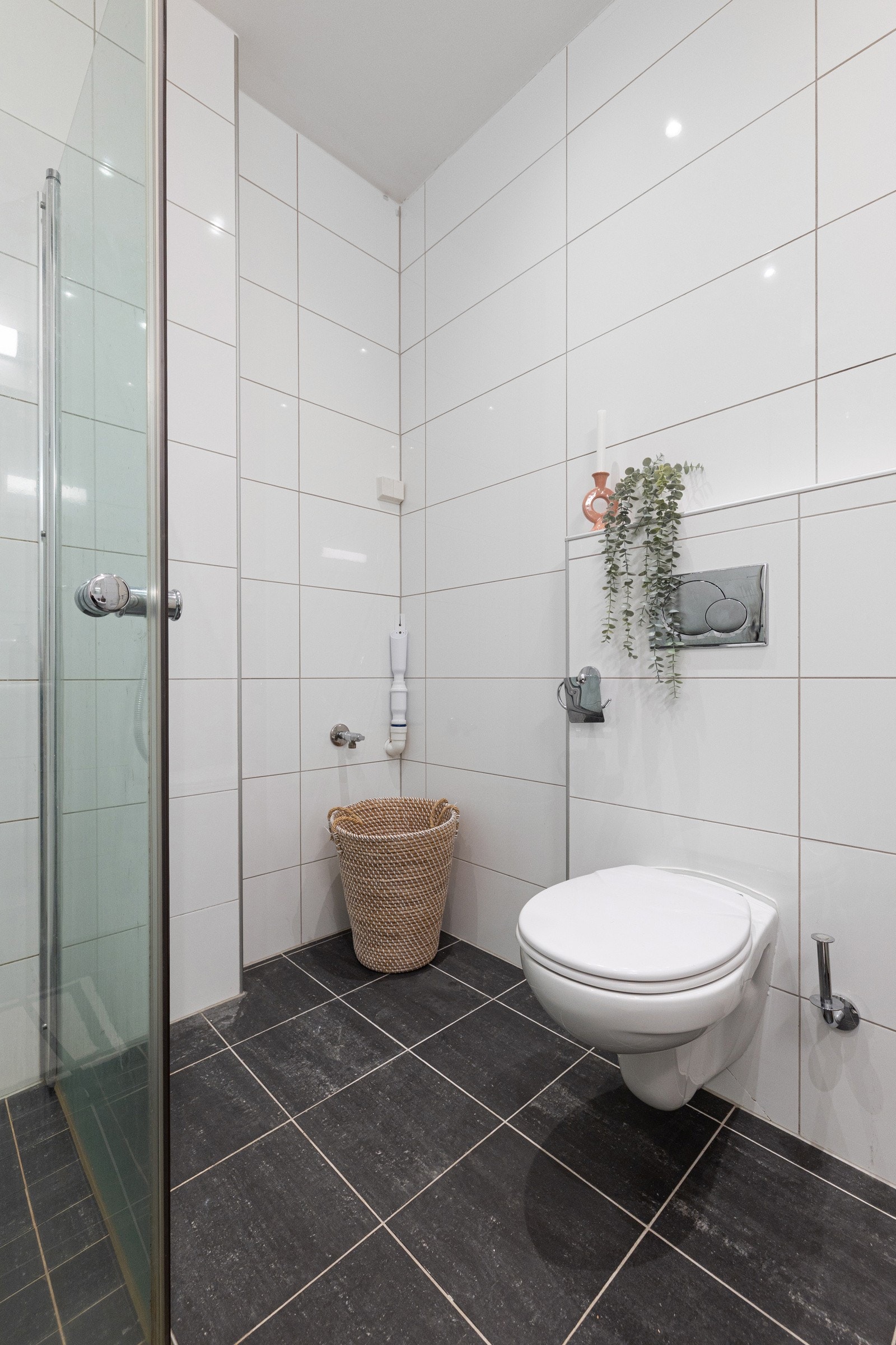 Badet er utstyr med gulvvarme, naturlig avtrekk, opplegg for vaskemaskin, rørfordelingsskap, stoppekran, veggmontert wc og dusjhjørne med glassdører og ettgreps dusjbatteri i rustfritt stål med to dusjhoder (håndholdt og regnfall). Galleribilde