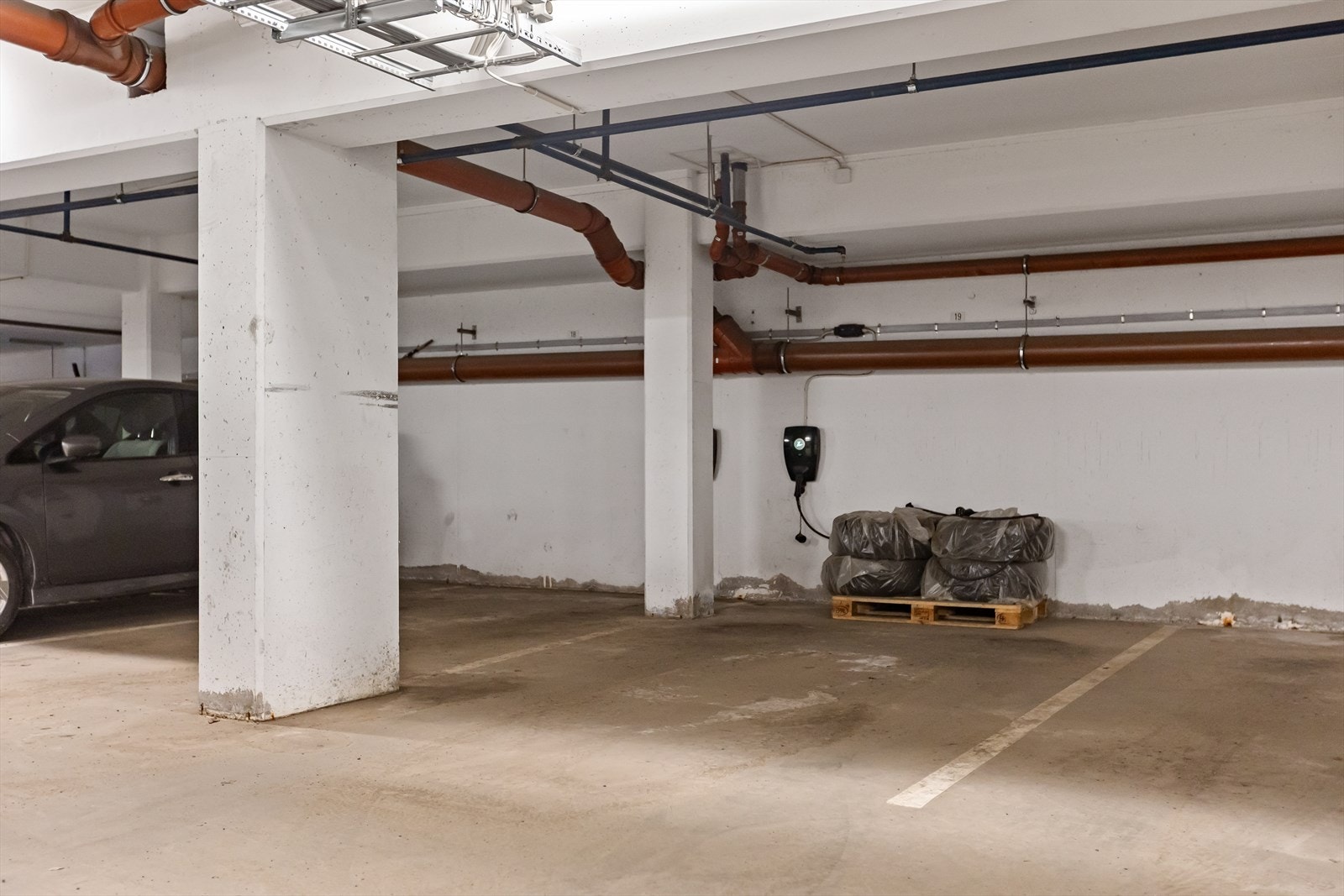 Med leiligheten følger en egen parkeringsplass i felles garasjeanlegg, utstyrt med elbillader. Galleribilde