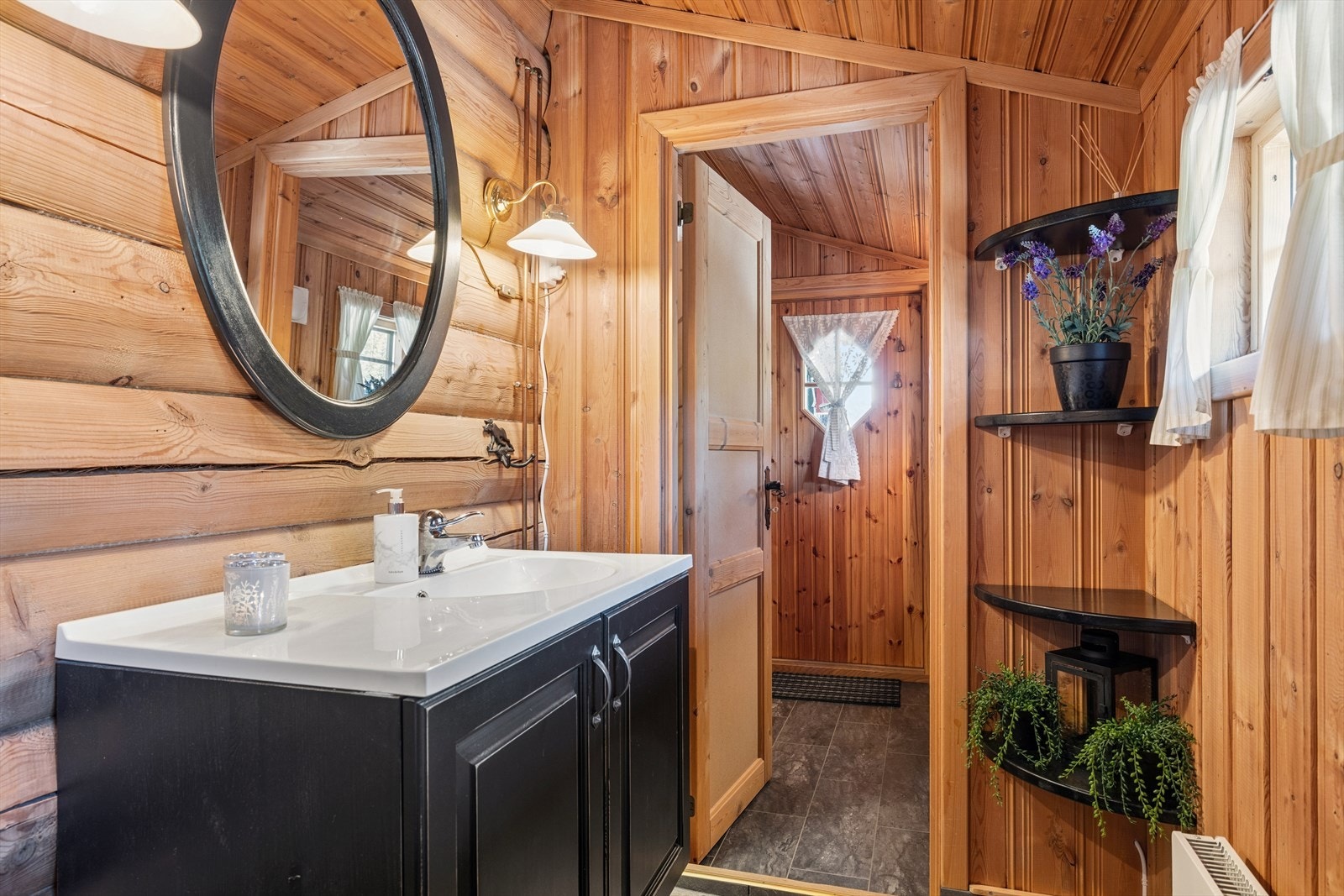 Badet har flislagt gulv med sokkelflis, panel på veggene og en aldringsmalt baderomsinnredning. Galleribilde