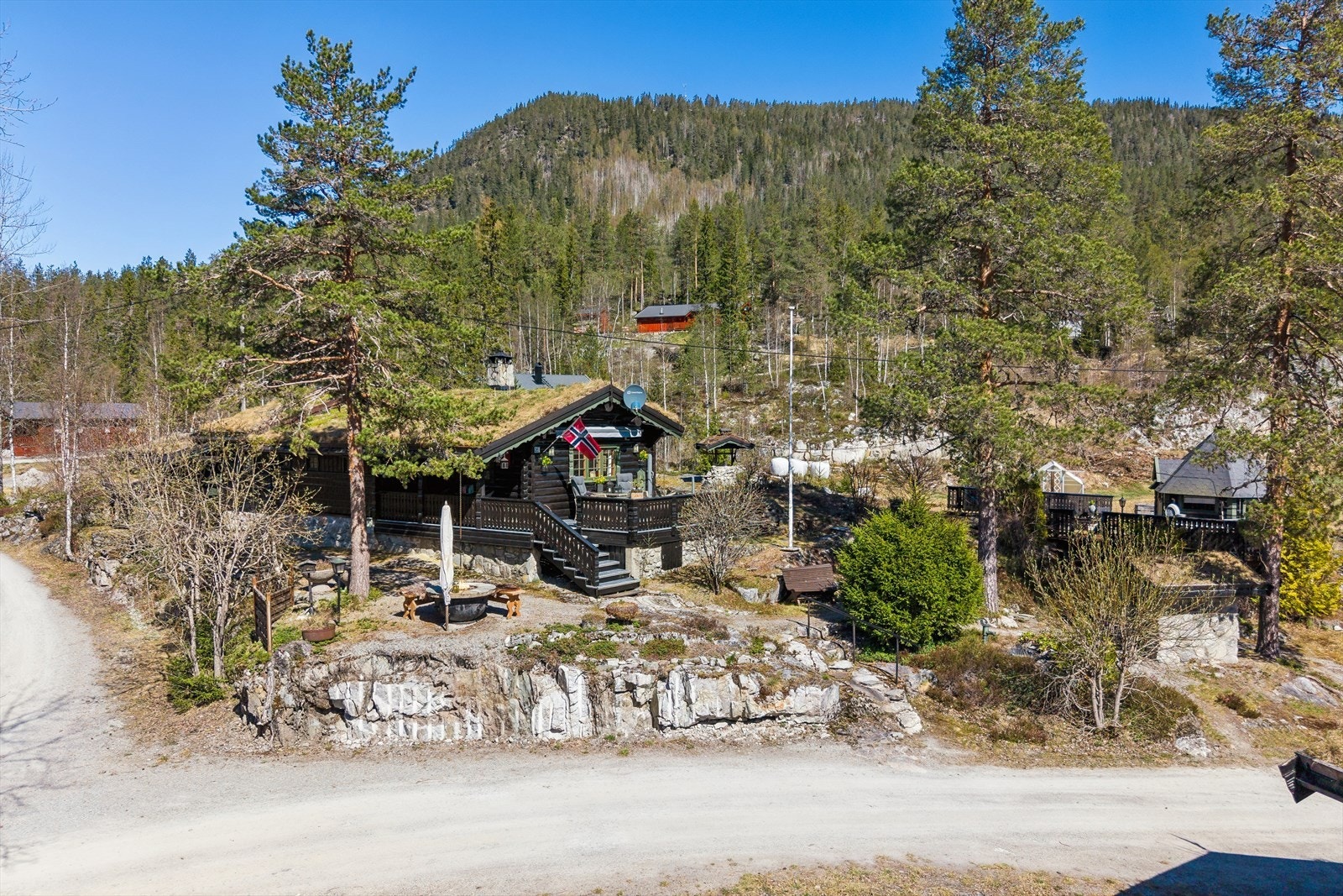Eiendommen ligger på en naturtomt med flere uteplasser, garasje, grillhytte og et uthus. Galleribilde