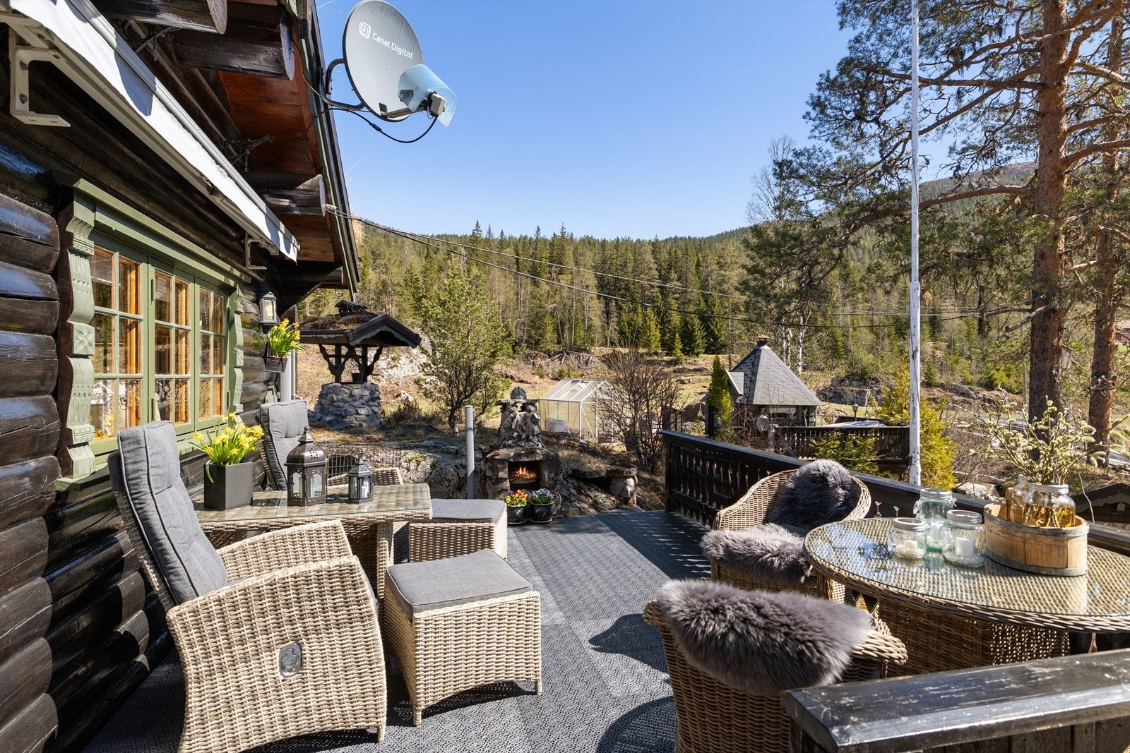 Fra terrassen ser man ut over eiendommen med grillhytte og naturtomt. Galleribilde