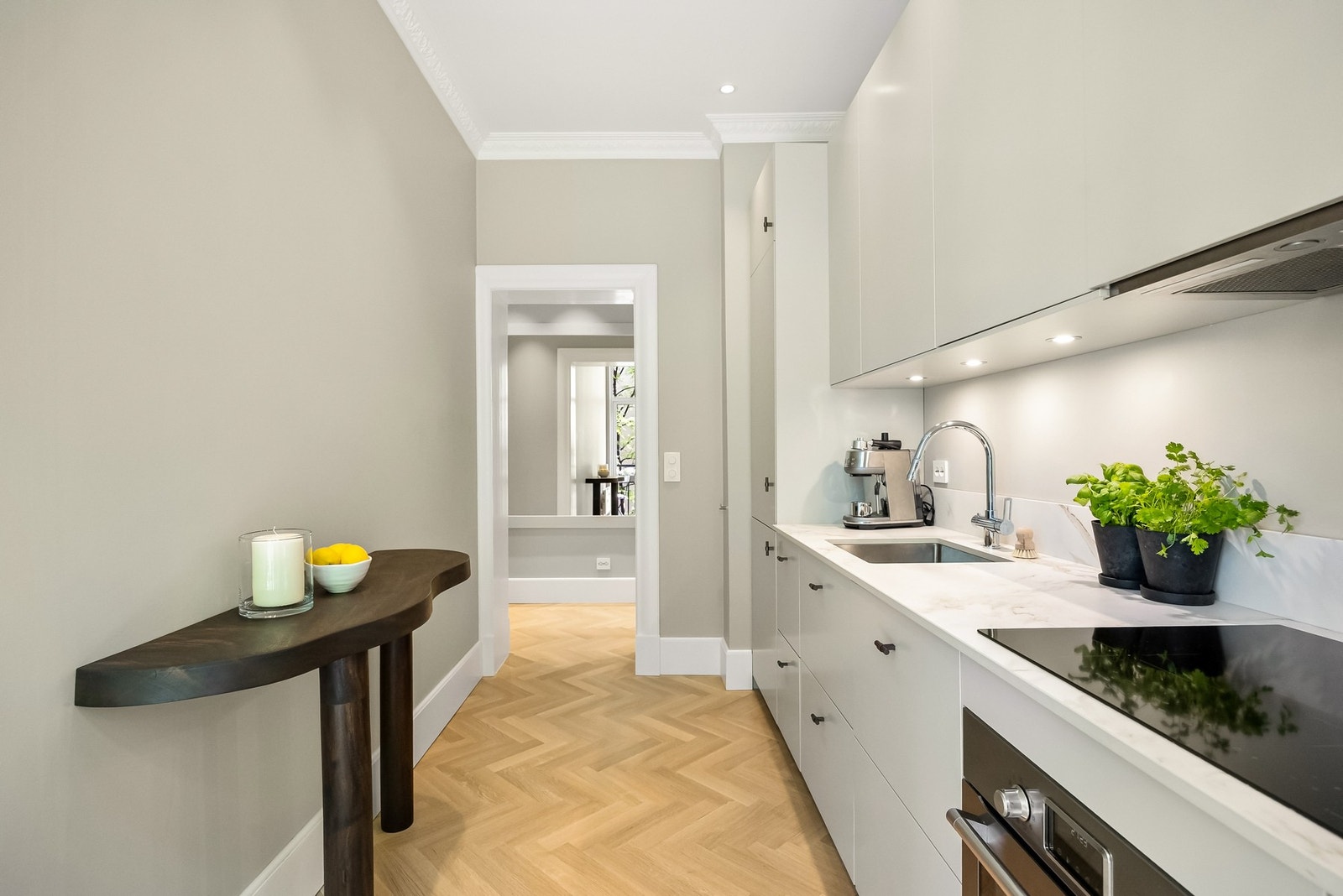 Kjøkkenet er innredet med slette fronter, overskap med benkebelysning og lav backsplash-plate på vegg. Galleribilde