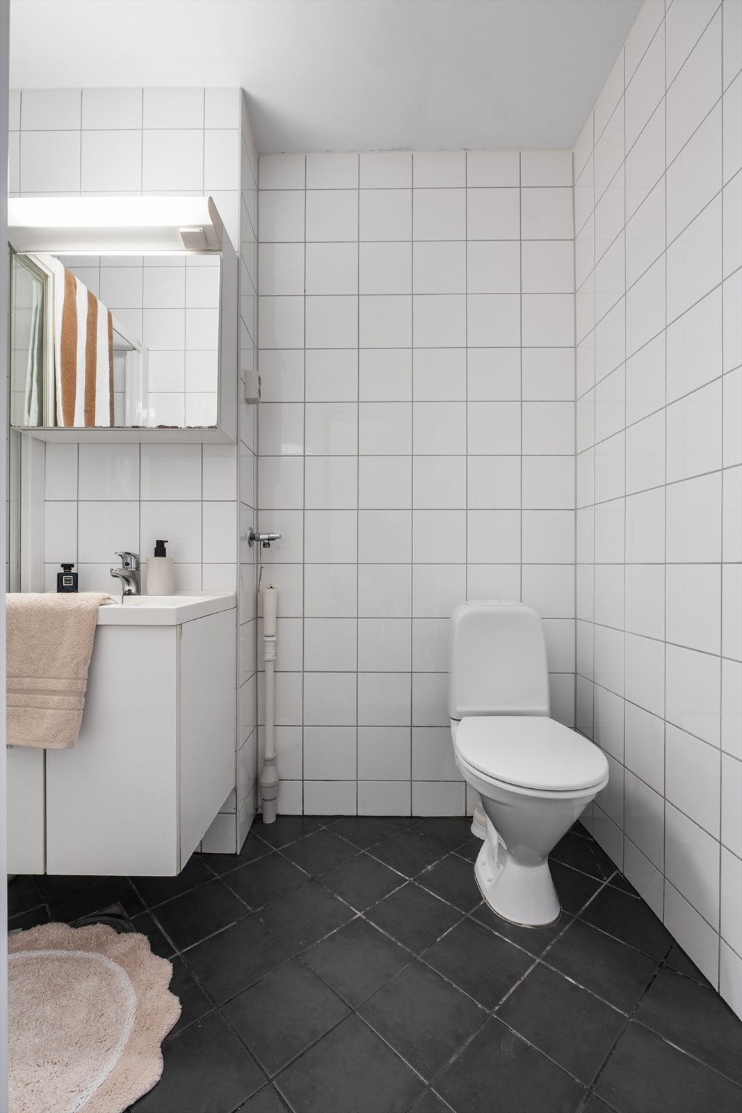 Badet er innredet med dusjkabinett, servant med underskap og opplegg for vaskemaskin Galleribilde