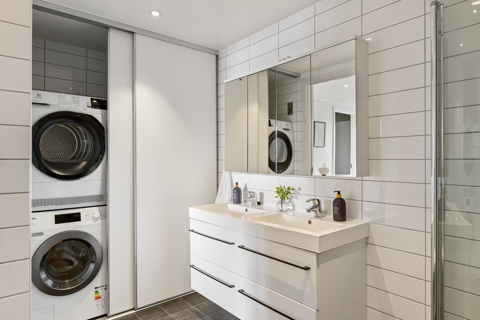 Badet har en smart vaskeromsløsning med opplegg for vaskemaskin, skjult bak skyvedører. Galleribilde