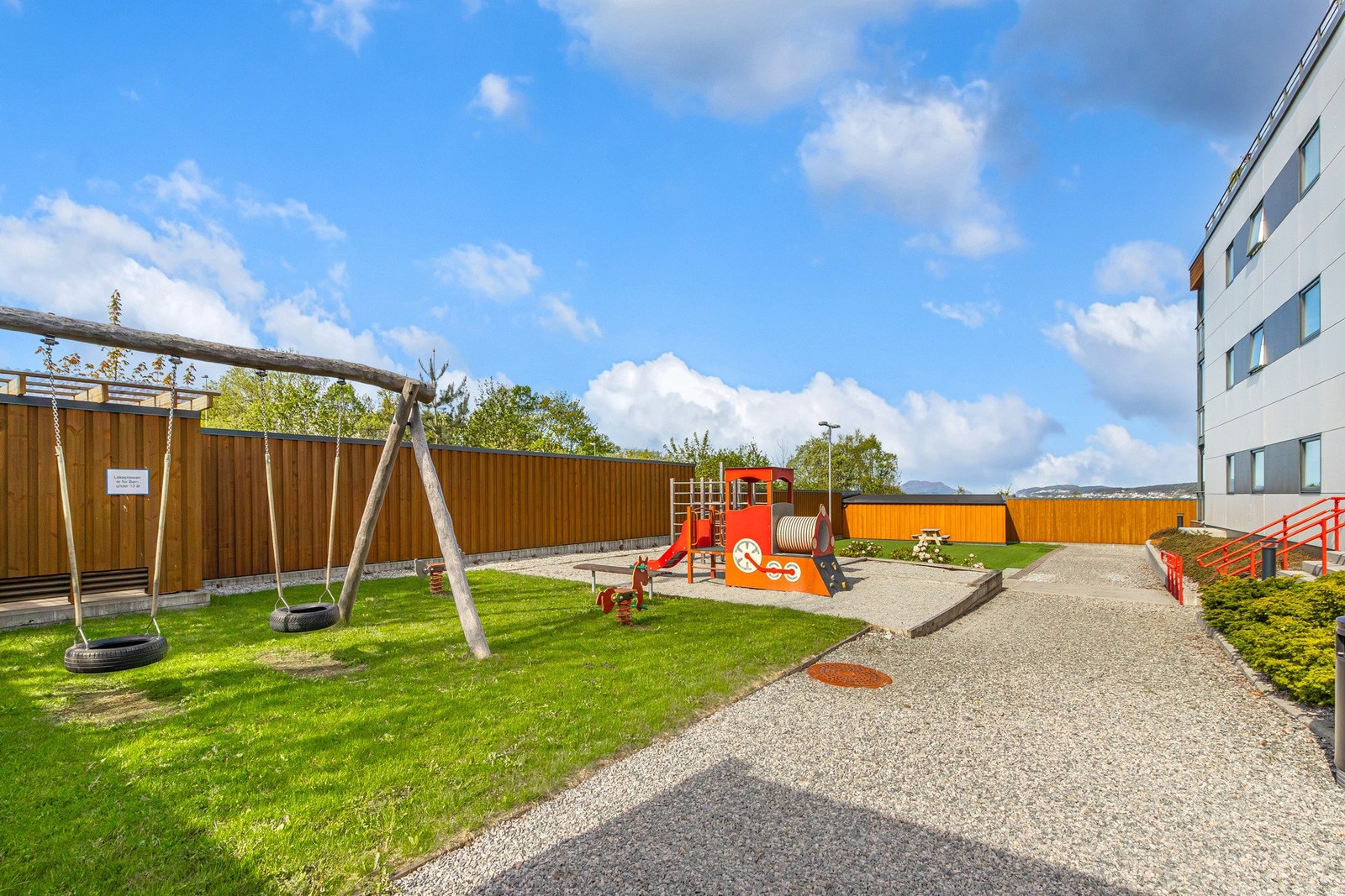 Tomten som er felles er opparbeidet med asfalt, beplantning og lekeplass. Galleribilde