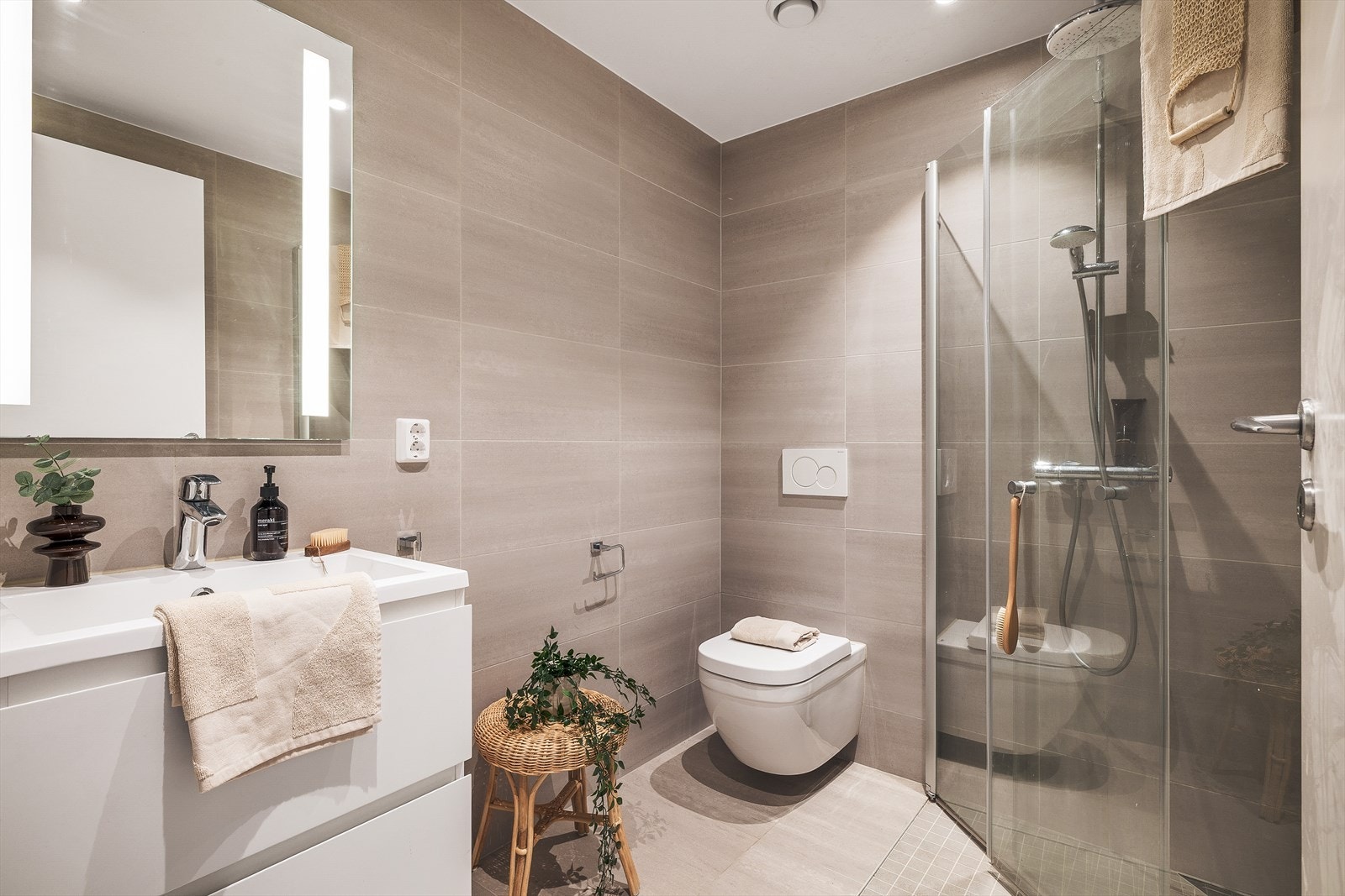 Badet i 1. etasje er helfliset, med varmekabler i gulv. Rommet har innredning med nedfelt servant, veggmontert toalett og dusjvegger/hjørne. Galleribilde