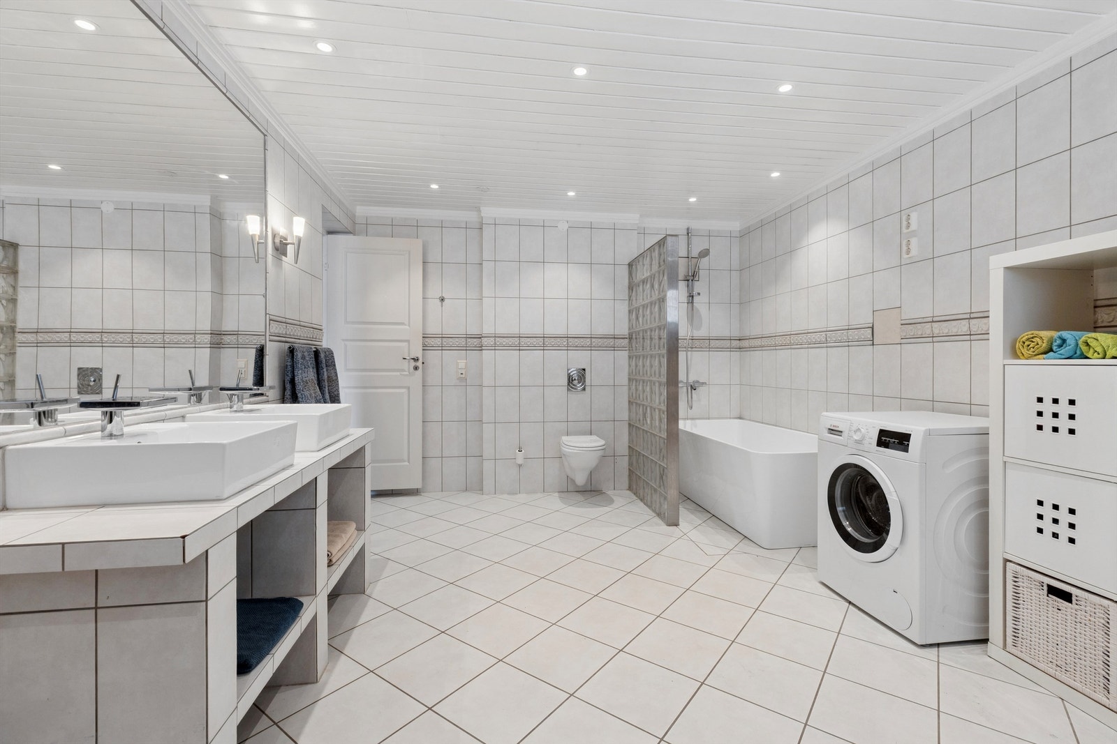 Stort, flislagt og delikat bad med både badekar og dobbel servant, som gir god komfort og funksjonalitet. Vegghengt WC bidrar til et rent og moderne uttrykk. Rommet er opprinnelig byggesøkt som kjeller og ikke godkjent til varig opphold. Galleribilde
