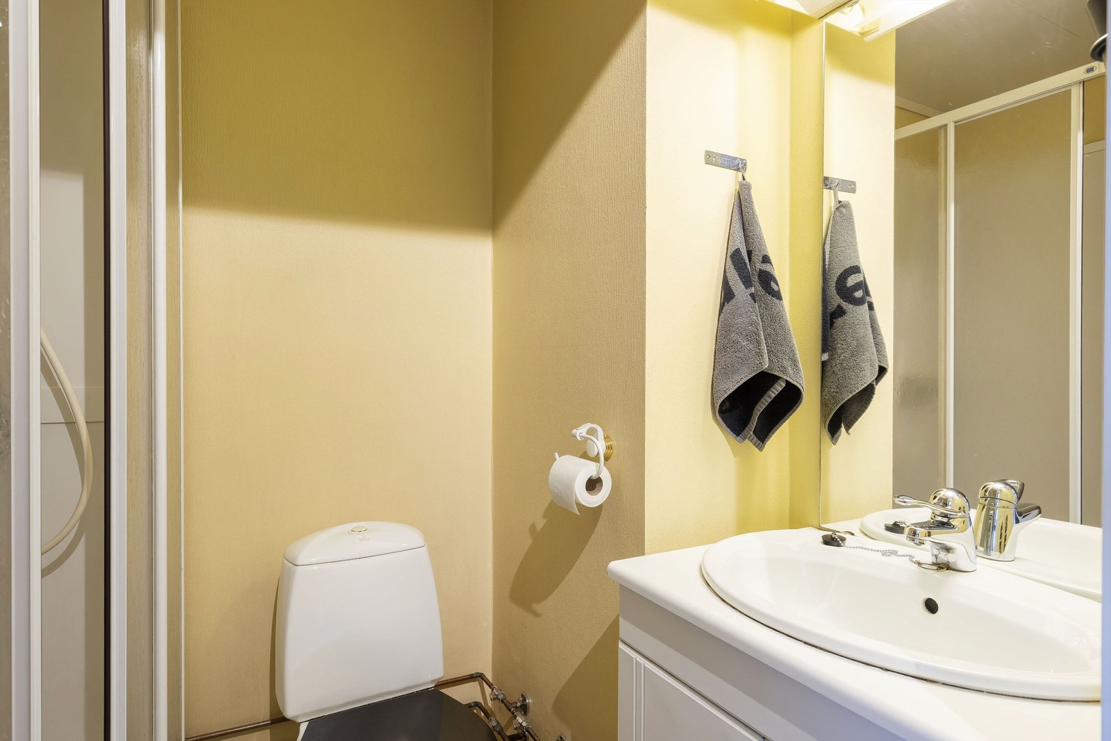 Bad med varmekabler i gulv. Dusjkabinett, wc og servantinnredning. Galleribilde