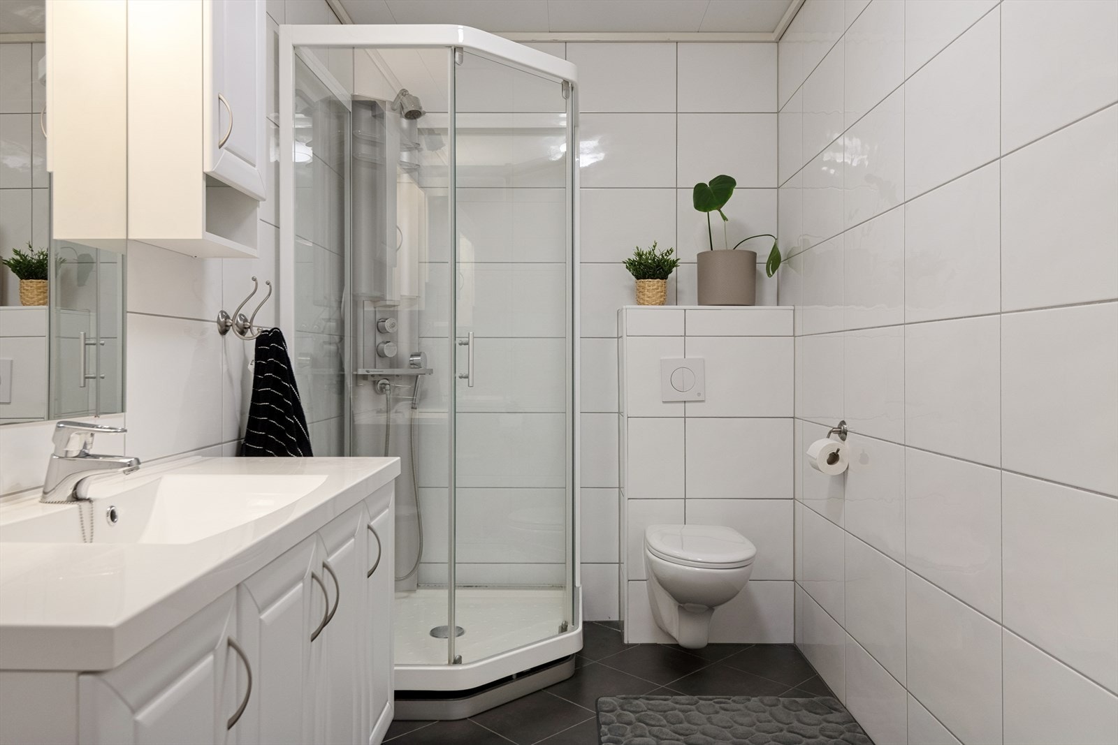 Badet er innredet med dusjkabinett, vegghengt toalett og baderomsinnredning med servant. Galleribilde