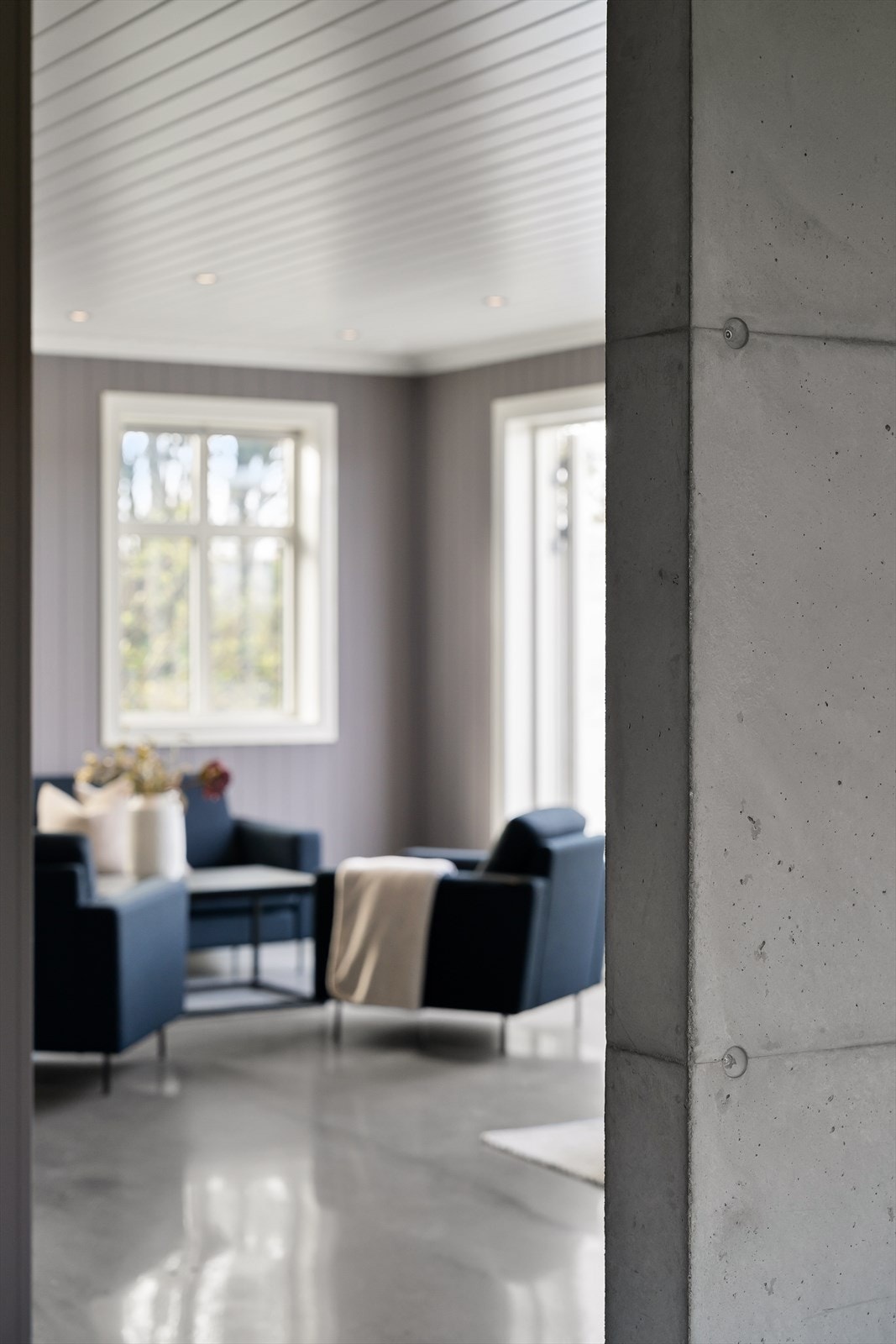 Et glimt inn i stuen fra gangen viser de gjennomgående materialvalgene. Galleribilde