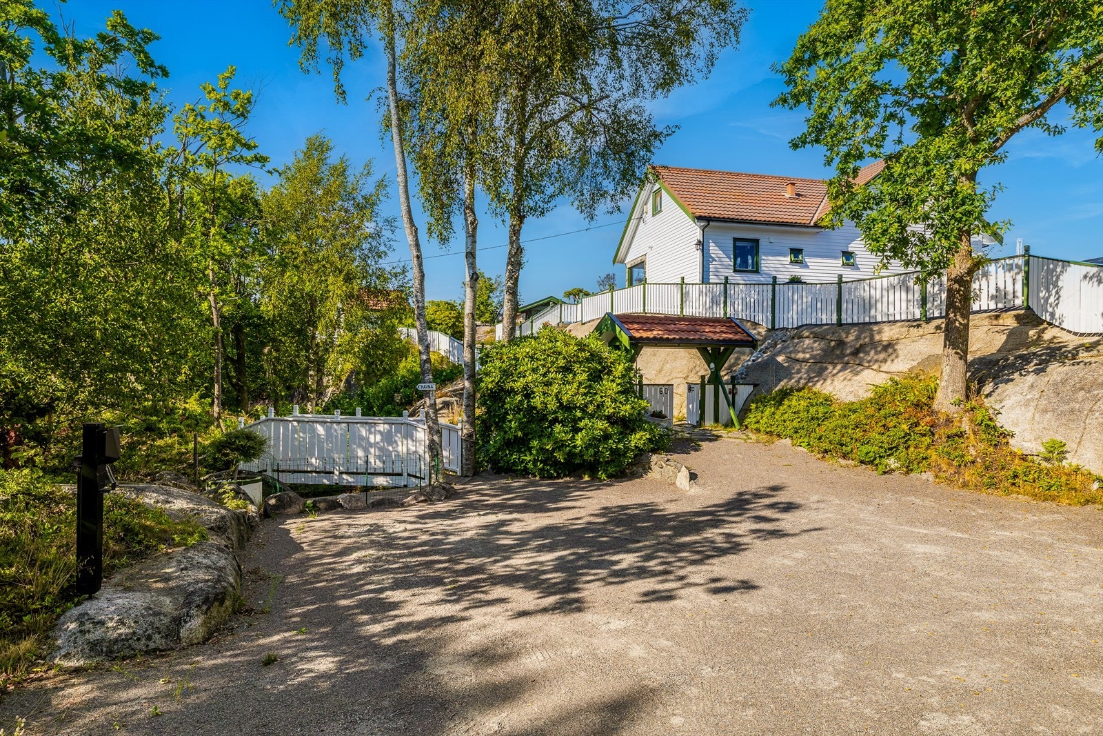 Bilveien går helt frem, og hytta har en gruslagt gårdsplass med lader for elbil. Galleribilde