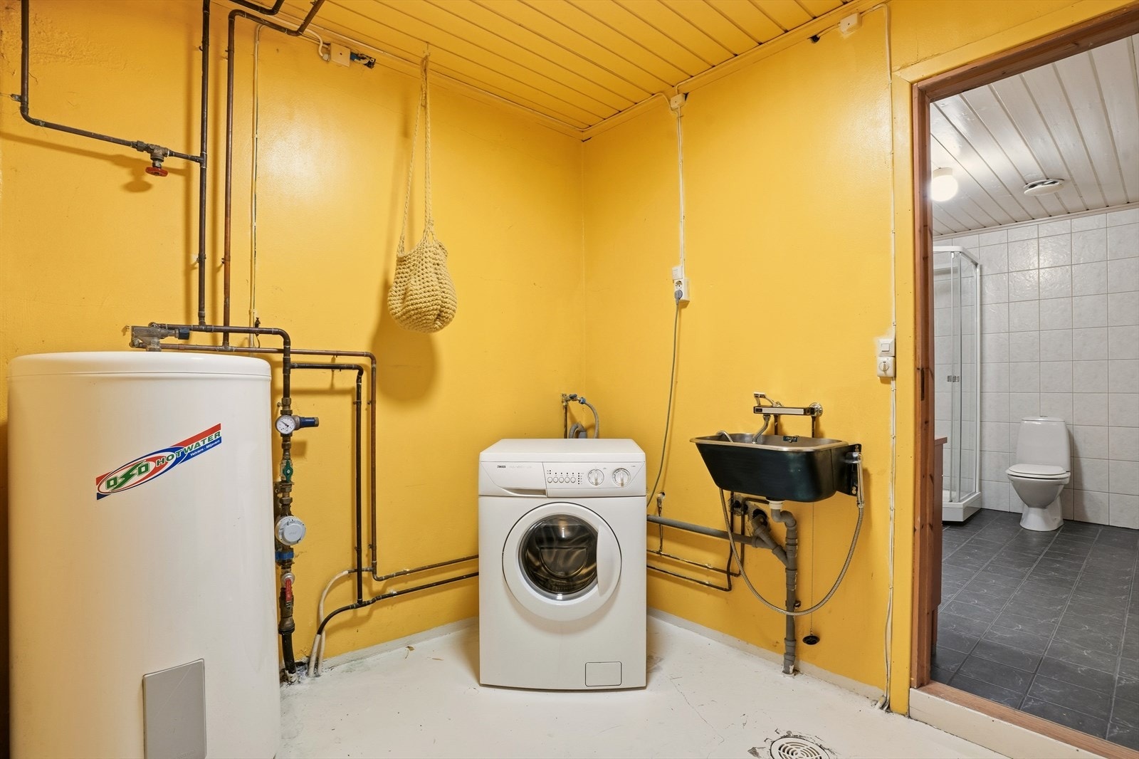 Vaskerom inn fra badet. Her med varmtvannsbereder, utslagsvask, og eget sluk i gulvet. Galleribilde