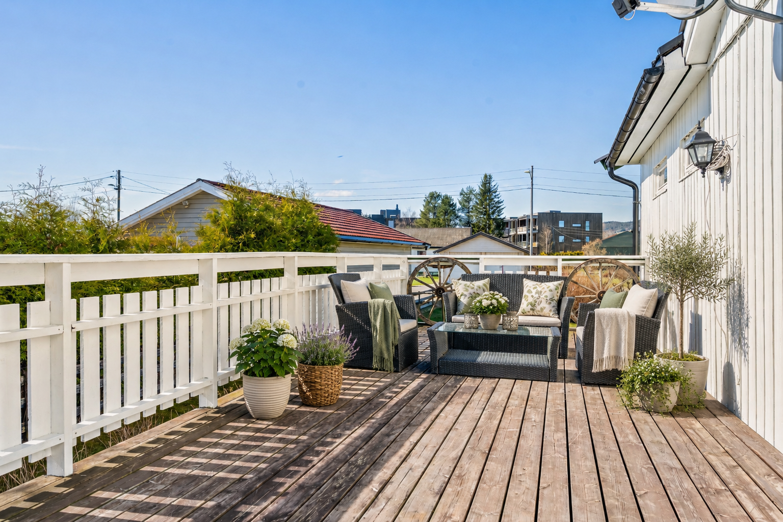 Eiendommen har store solrike uteplasser. Terrassen har tilkomst fra stuen, og har plass til godt med møblement, grill og planter. Puter, pledd og planter er generert av KI. Galleribilde