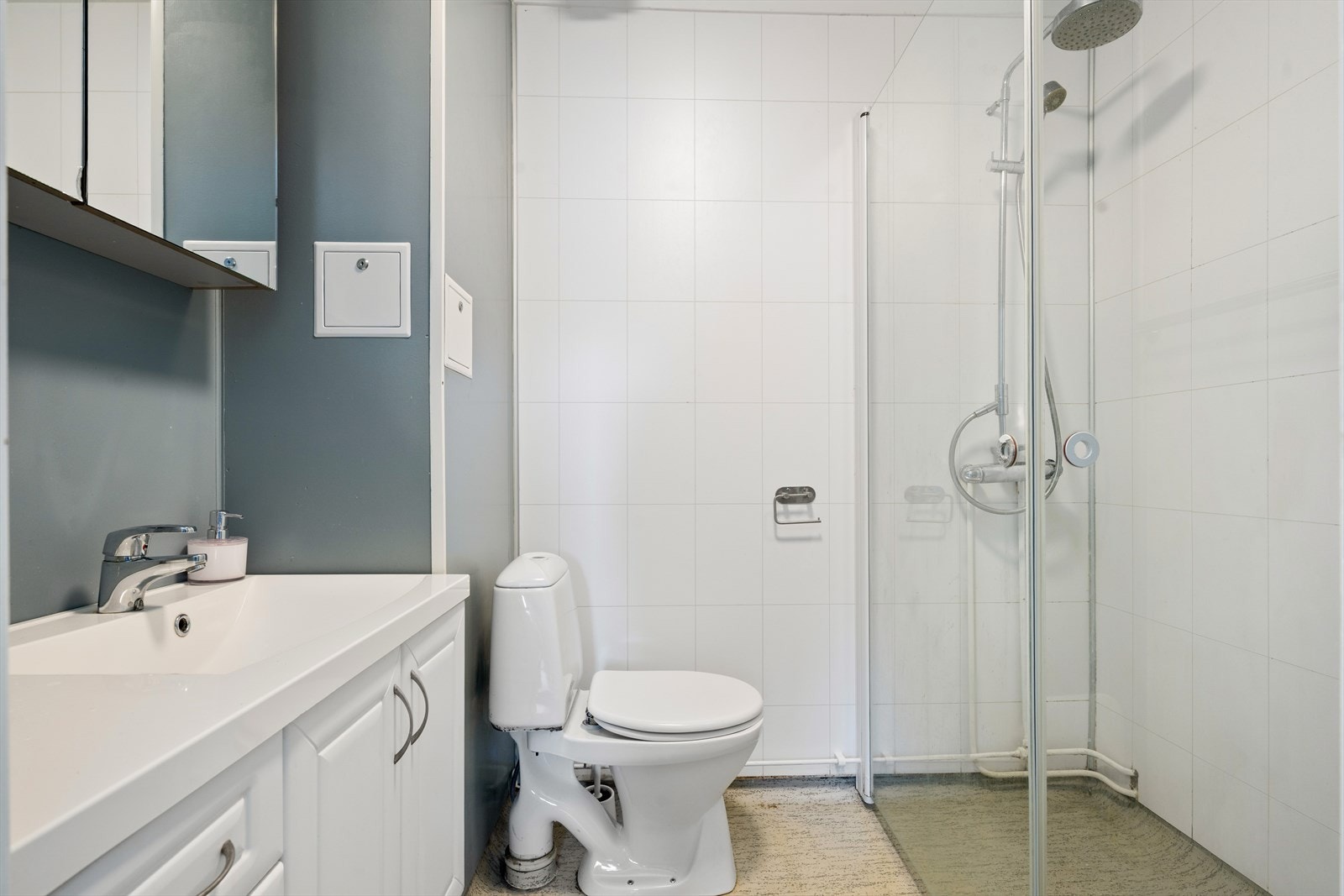Badet er innredet med en stor servant med skap, speil med oppbevaring, toalett og dusjhjørne med glassvegger. Galleribilde