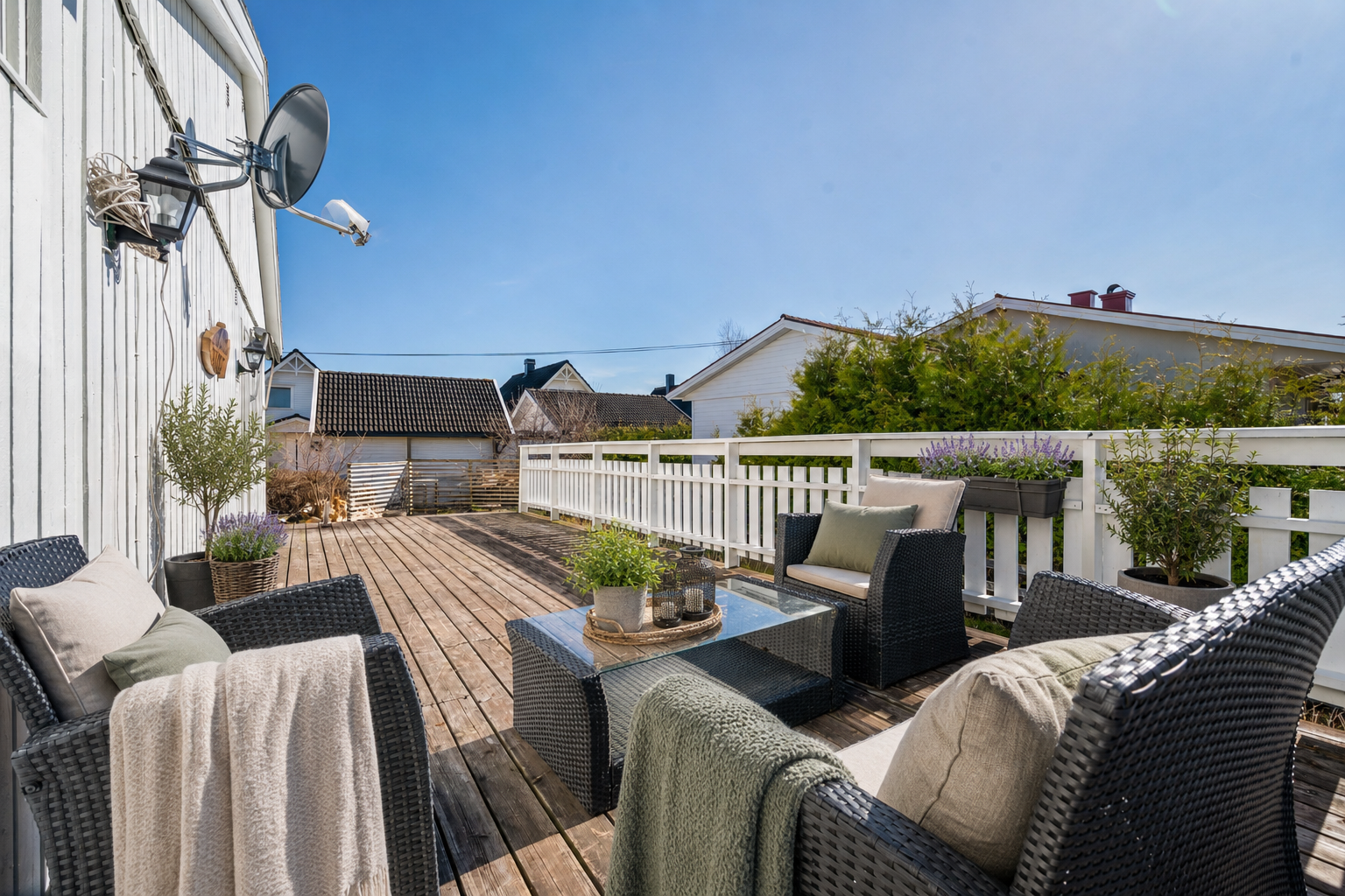 Fra terrassen kommer du videre ut i den flate og grønne tomten. Her er det god plass for trampoline, ballspill og sammenkomster. Puter, pledd og planter er generert av KI. Galleribilde