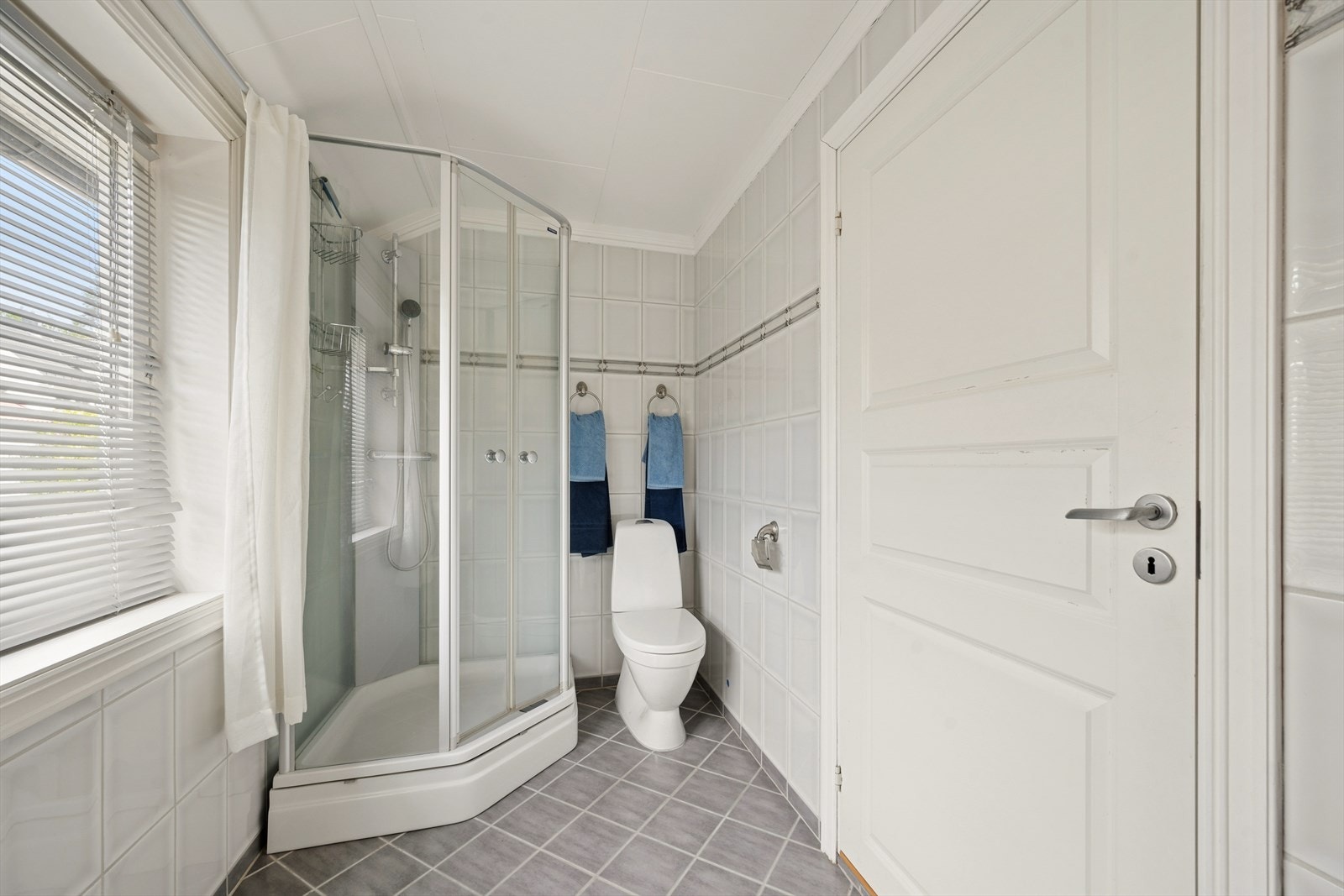 Badet er utstyrt med dusjkabinett, gulvstående klosett og baderomsinnredning med servant i helstøpt plate. Galleribilde