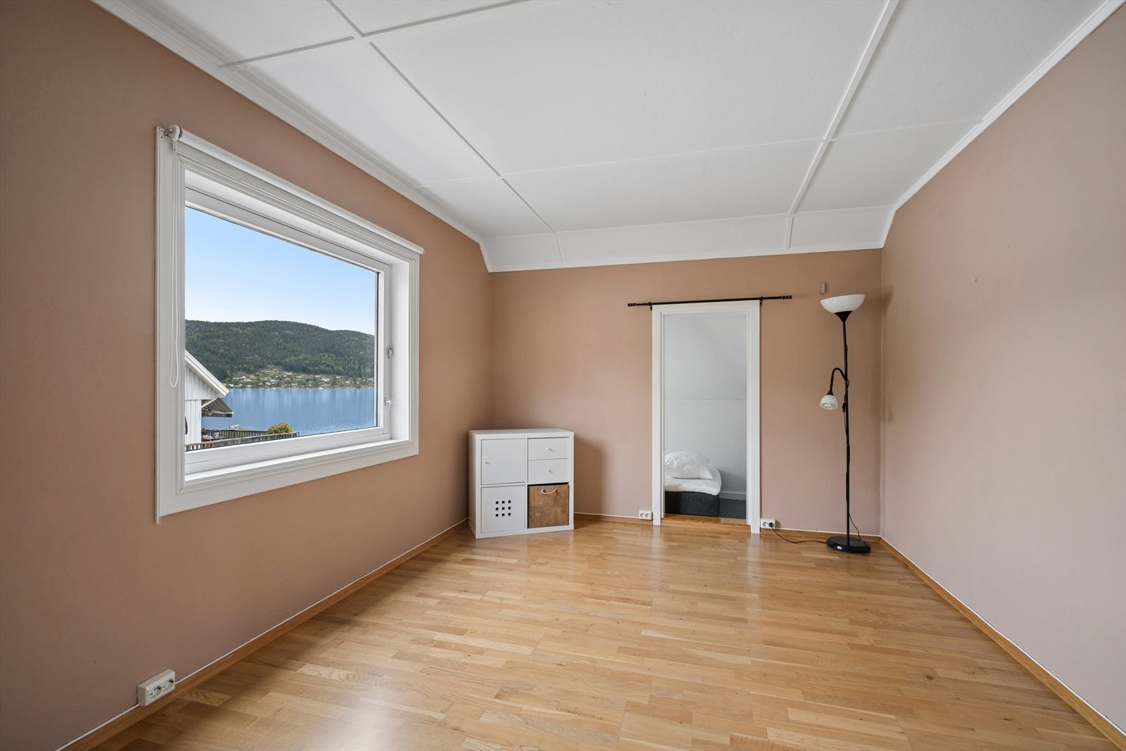 Romslig soverom i andre etasje med parkett på gulvet og utsikt mot fjorden. Galleribilde