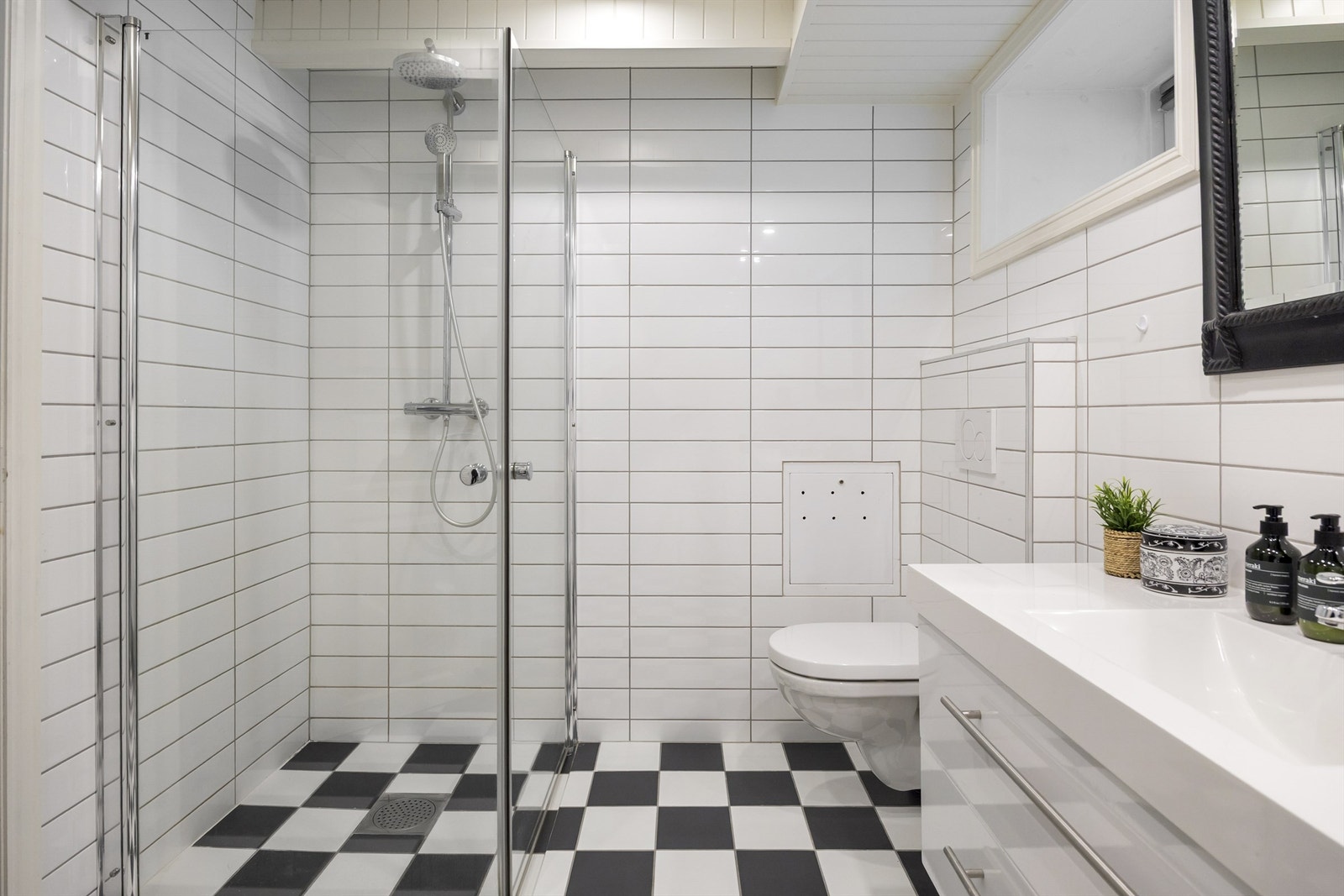 Badet er innredet med vegghengt klosett, servant nedfelt i innredning og dusjhjørne med svingbare glassdører, regndusj og hånddusj. Elektrisk styrt vifte Galleribilde