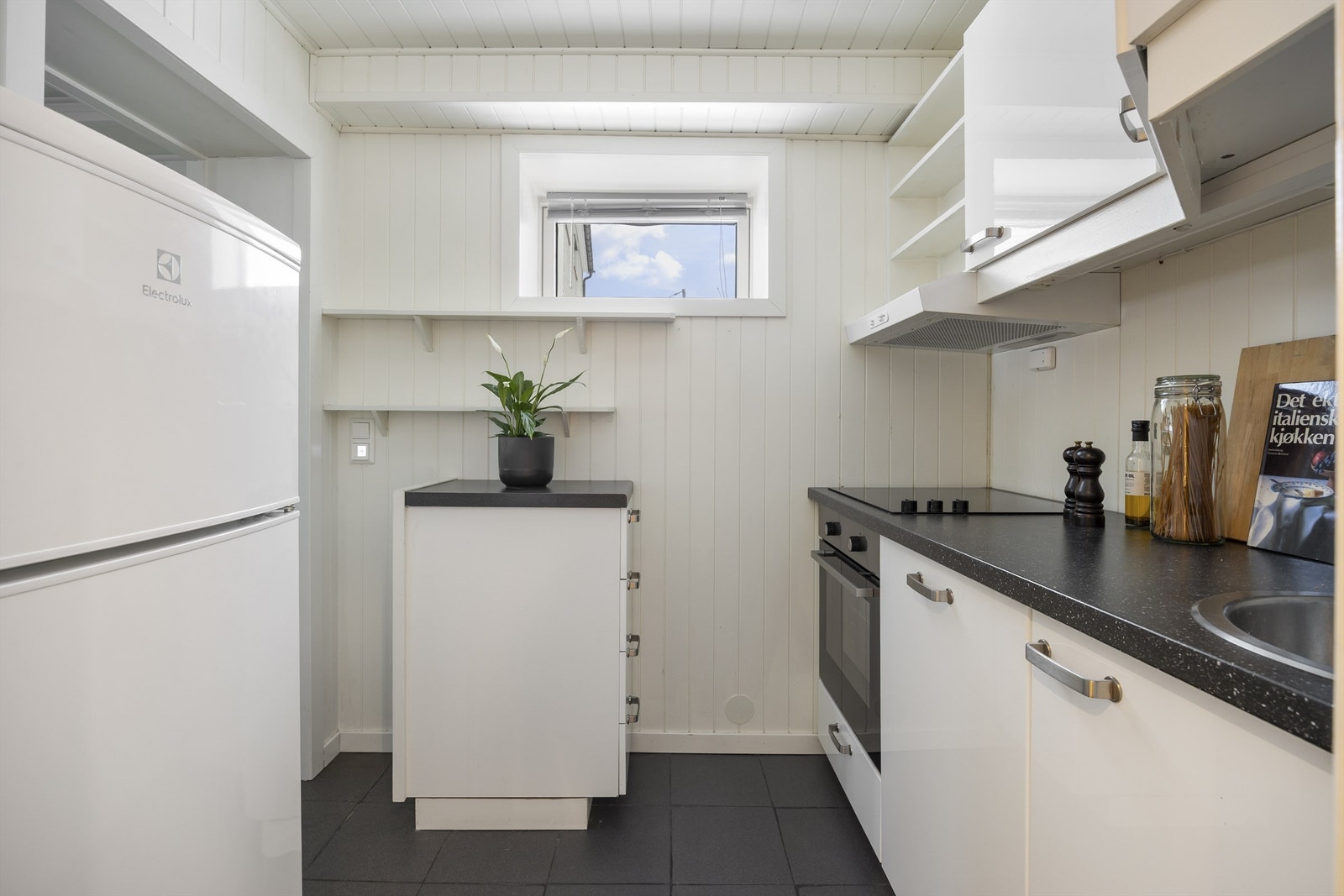 Kjøkkeninnredning med glatte fronter. Laminat benkeplate med nedfelt vaskekum. Integrert induksjonstopp, stekeovn og oppvaskmaskin Galleribilde