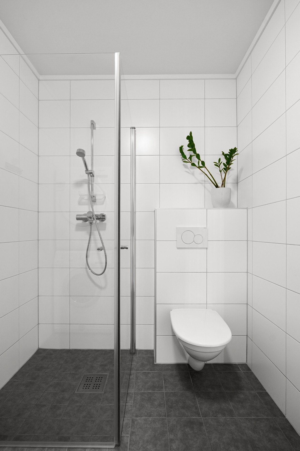 Badet er utstyrt med dusjhjørne, baderomsinnredning, opplegg for vaskemaskin og veggmontert wc Galleribilde